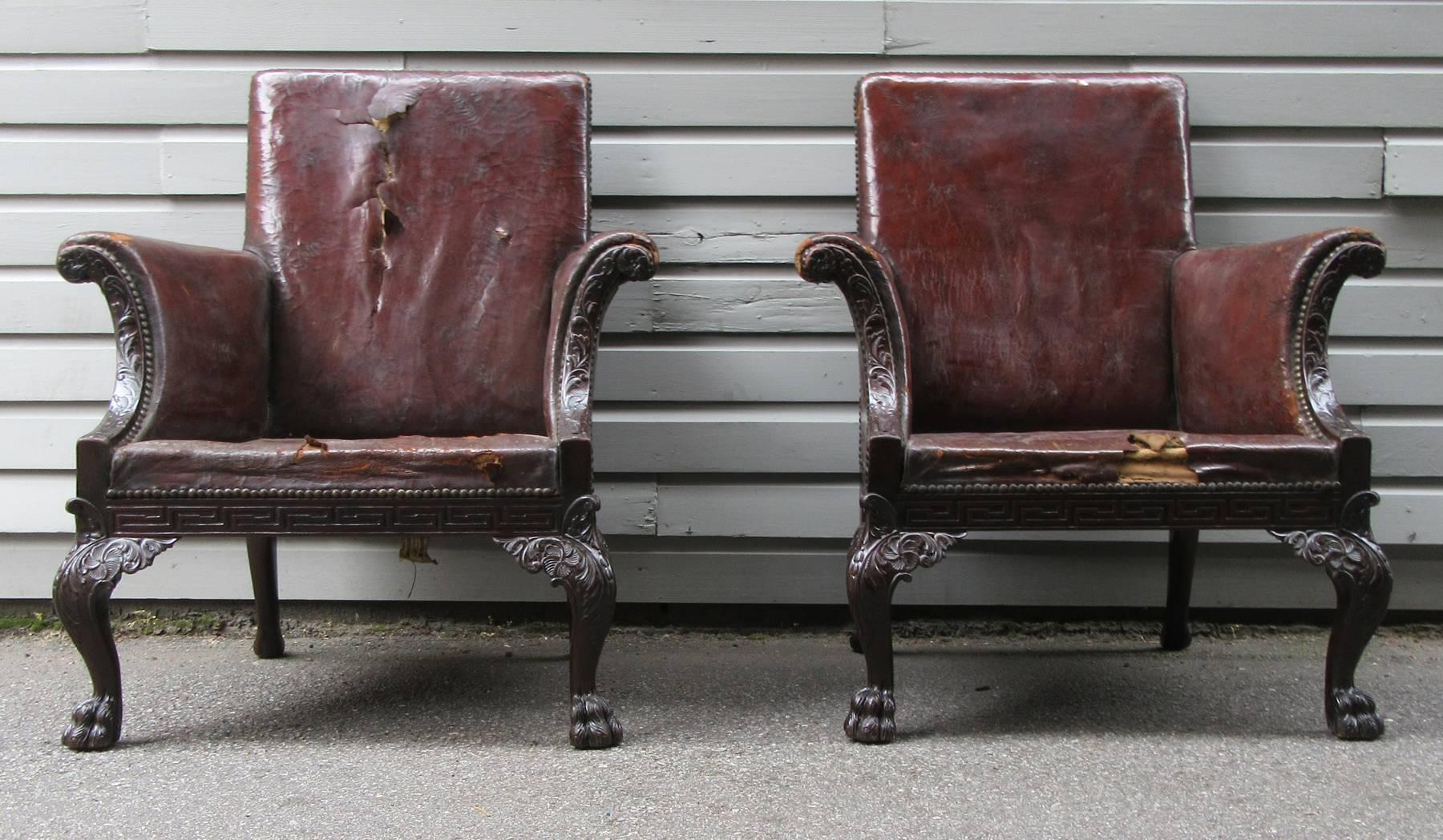A stately pair of large Irish Chippendale mahogany library chairs, made in the late 18th-early 19th century, with intricately carved frames featuring acanthus leaves, rosettes and hairy paw feet. The frames are in excellent condition, however the
