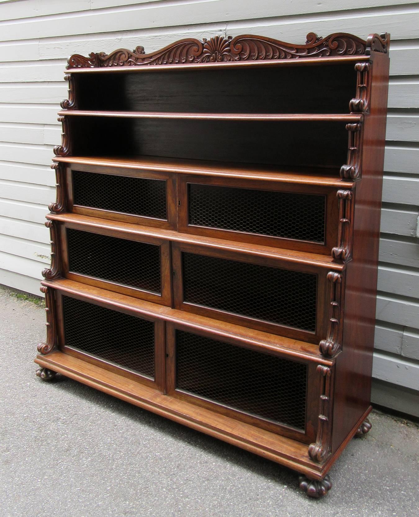 A West Indies Regency style rosewood bookcase, circa 1820, featuring six-tiered shelves with three wire cabinet doors and H-shell, wave, scroll and shell carvings. This Caribbean bookcase was likely from Jamaica or Barbados.