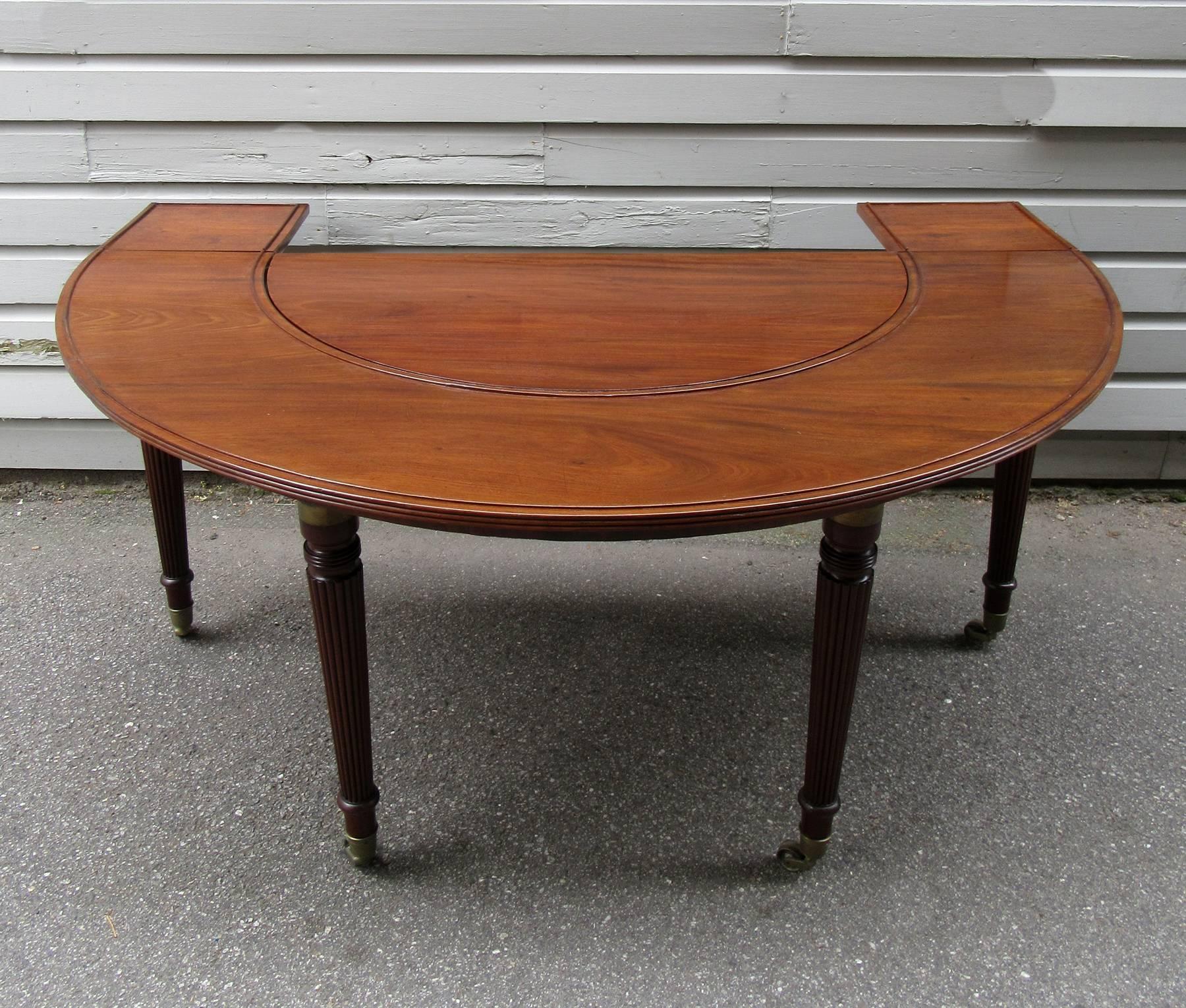 An English Regency mahogany social table, circa 1810, in classical Gillows design featuring removable reeded legs with brass cuffs and original cup casters. A similar table is featured in the book 