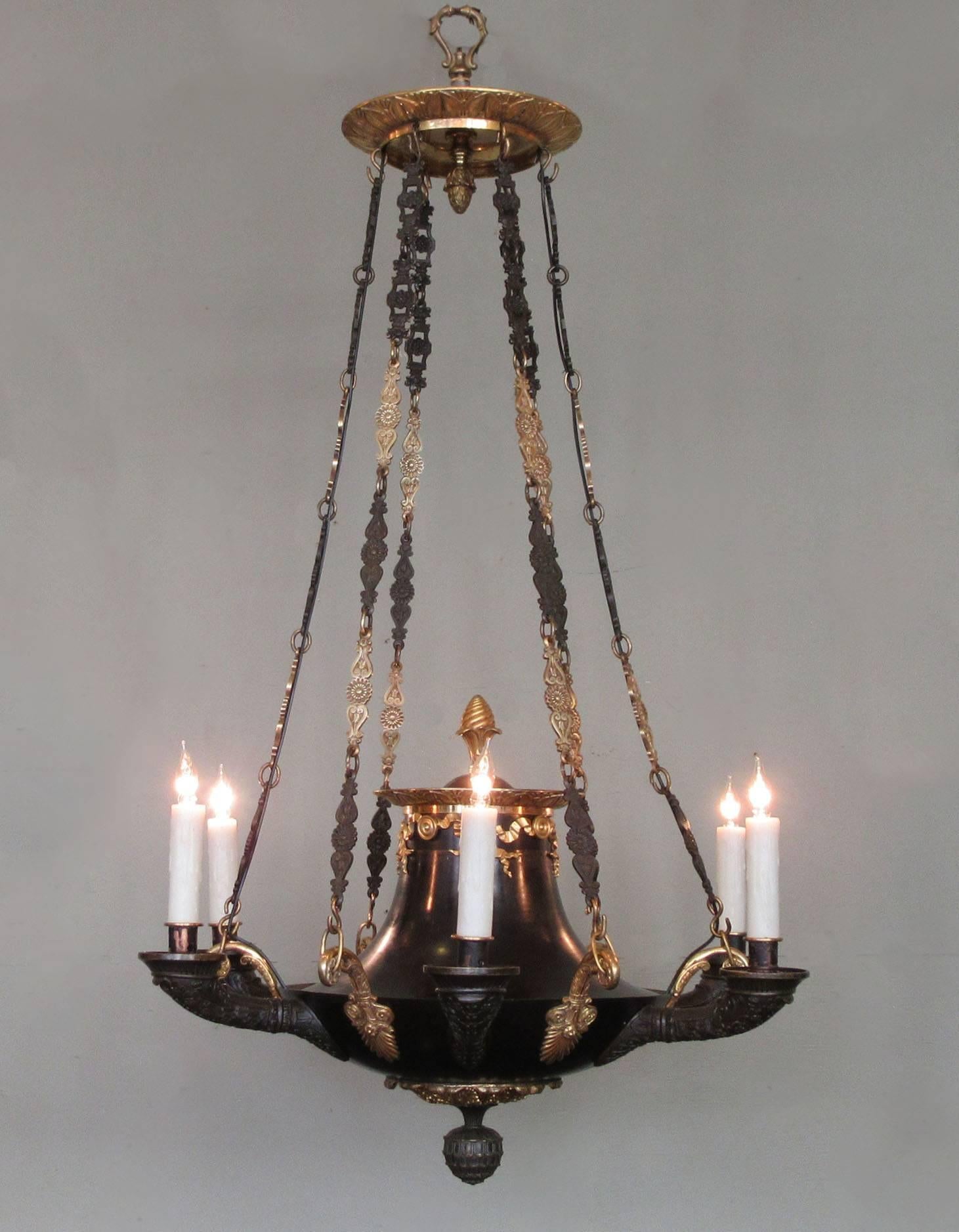 A very fine English Regency Argand (oil lamp) chandelier, circa 1810, featuring patinated and doré bronze, neoclassical motifs and six candle bulbs. The chandelier has been recently rewired with new porcelain sockets.
