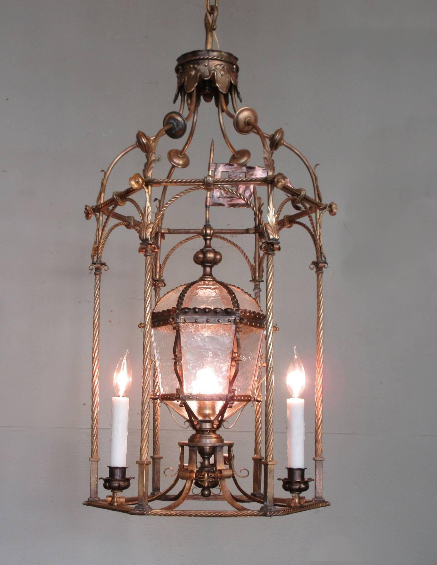A grand Venetian gilt tole lantern, circa 1840, featuring three candles and original centre oil lamp accented with tole and brass flag. The lantern has been cleaned and rewired with new porcelain sockets.  
  