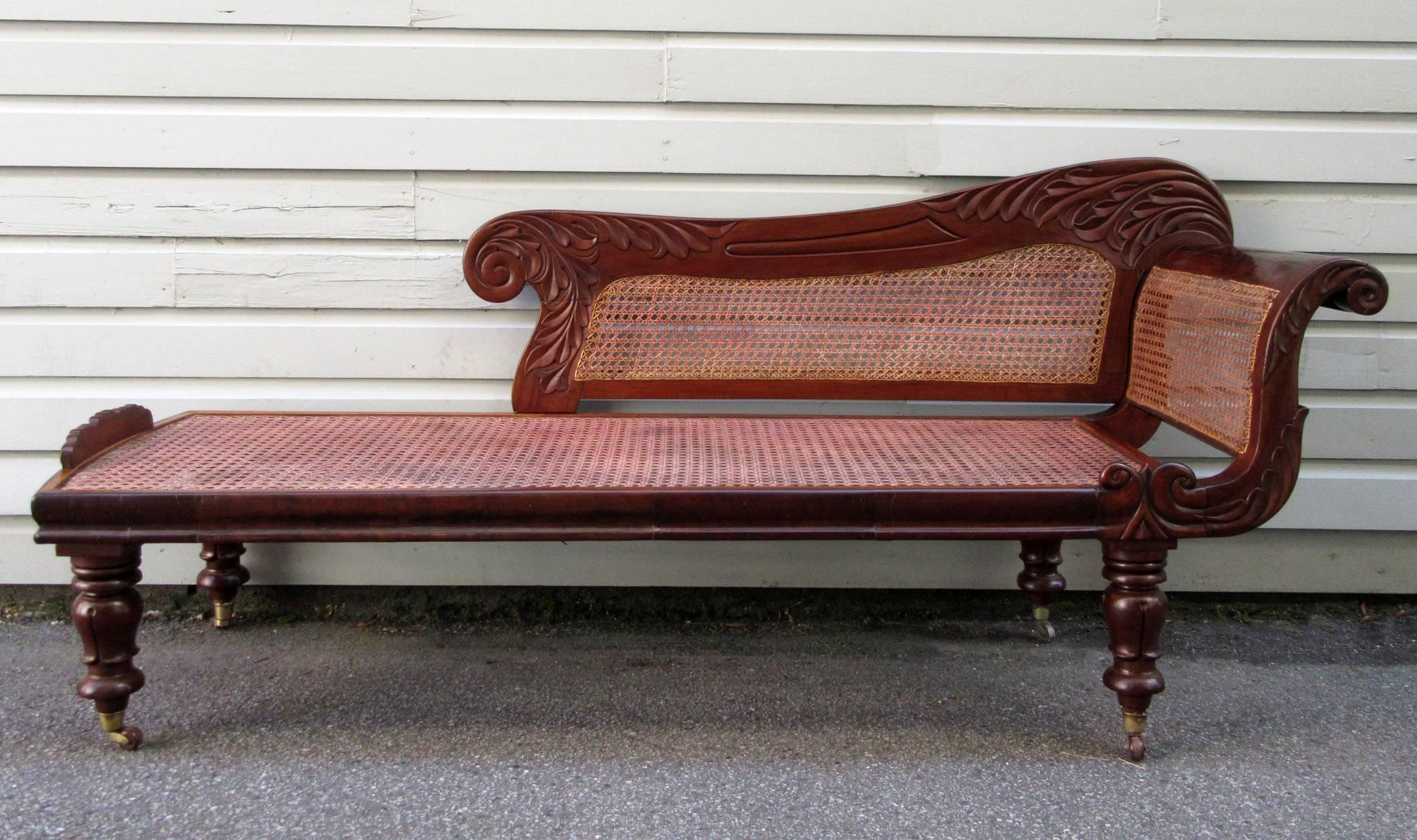 A 19th century Caribbean Regency mahogany recamier from Barbados, circa 1830, with handwoven caning, stylized acanthus and wave carvings and turned inverted tulip legs ending with original cup casters.