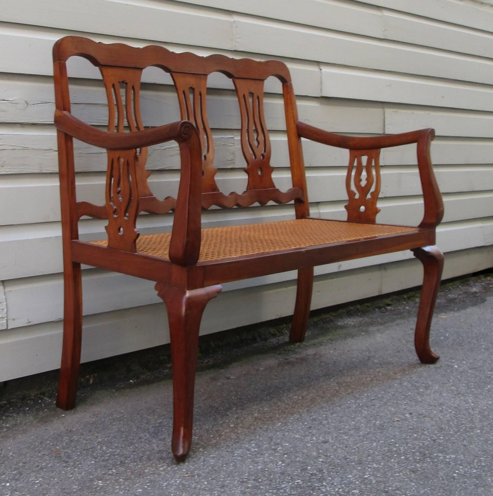 A graceful Caribbean Regency mahogany bench, circa 1840, featuring urn shaped splat back, scroll turned arms and cabriole leg ending in a spoon shaped foot. The caning is new and was hand-caned.
