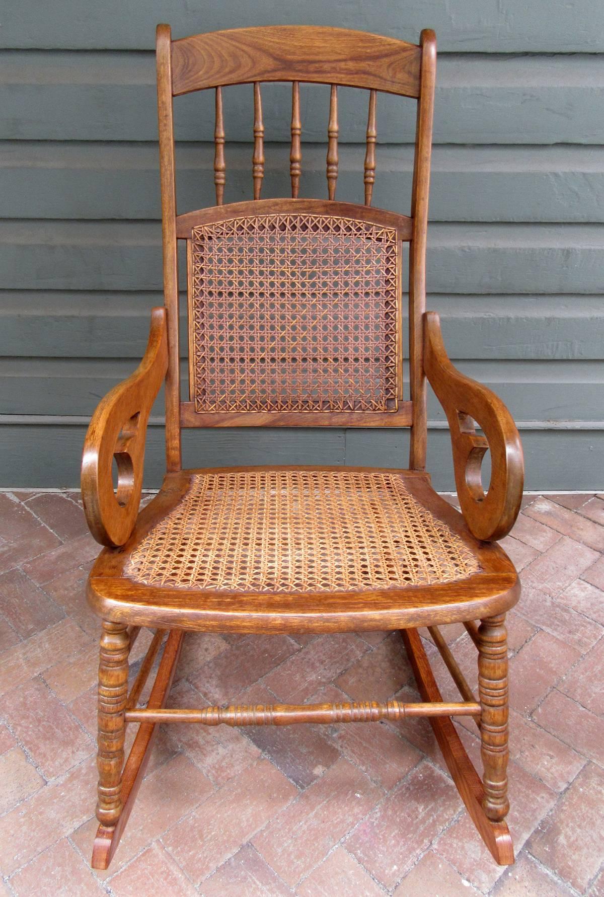 A Caribbean Regency mahogany and cane rocking chair from St. Croix, circa 1860, featuring scroll arms and handwoven caning. The mahogany is sun bleached and the runners were replaced with oak ones from being worn out from use. However, the rocking