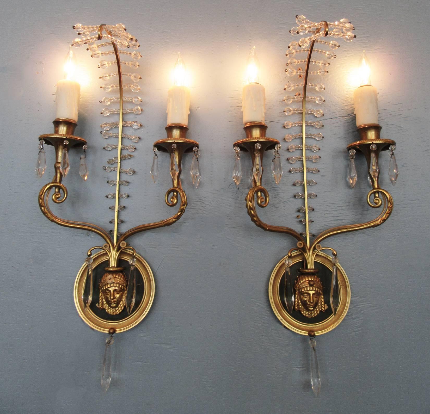 A pair of Egyptian style Italian bronze sconces, circa 1940, each featuring two candle bulbs with dark green patinated bronze medallion and projecting crystal feather or plume.