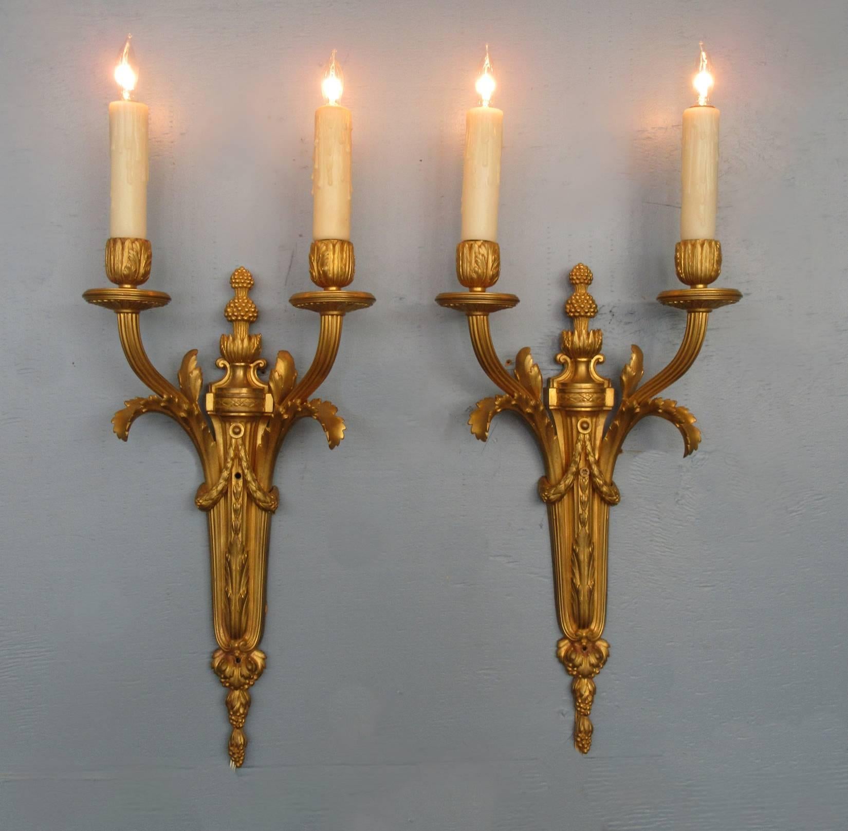 A finely cast pair of French Louis XVI bronze doré sconces, circa 1850, each two candle arms on a with quiver shaped base with foliate and floral details.