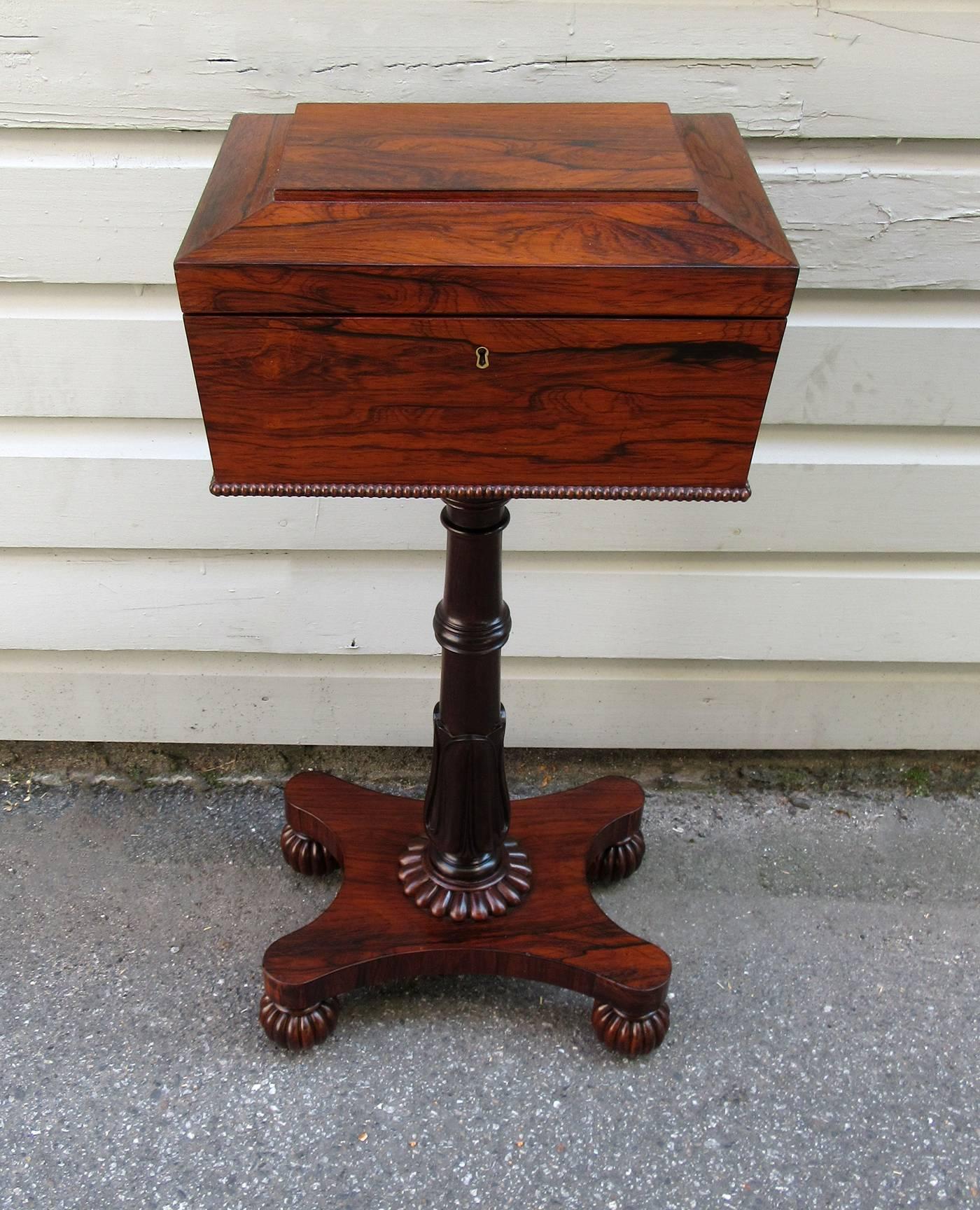 A very fine English Regency rosewood teapoy, circa 1820, featuring two removable and lined tea caddies and two centre containers lined with leather. The pedestal base features a tulip carving and four sandbox fruit feet.