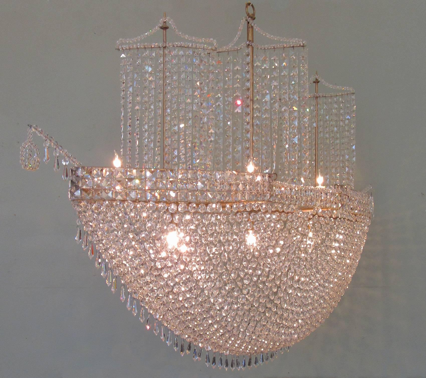 A monumental French crystal and tole ship chandelier, circa 1960, stretching almost five feet in length and featuring nine candle bulbs and three masts draped in square cut crystals. The chandelier has recently been cleaned and rewired with