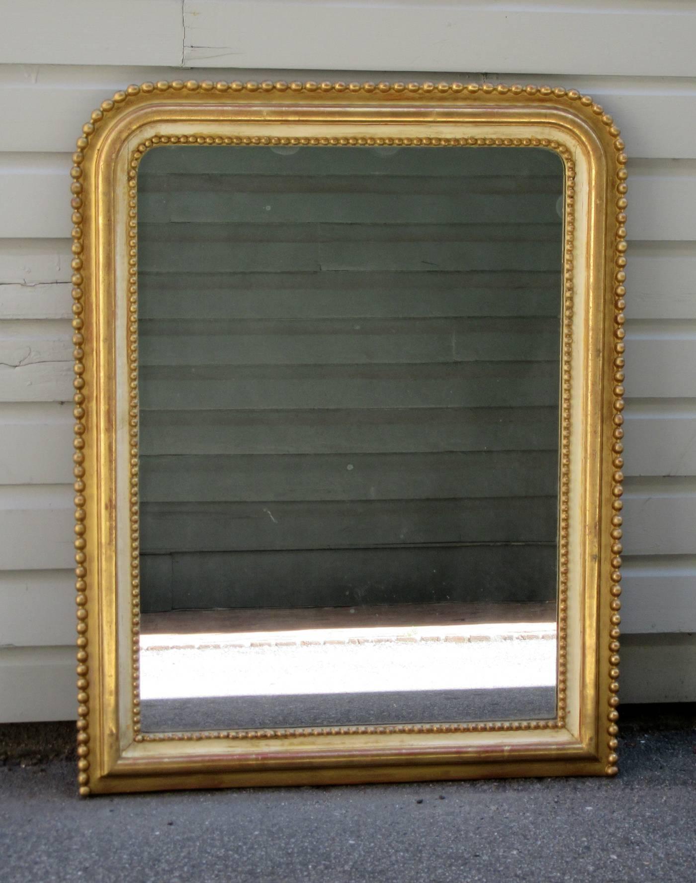 A 19th century French Louis Philippe mirror, circa 1840, with giltwood ball surround and ivory painted channel inset. The mirror plate is original to the mirror.