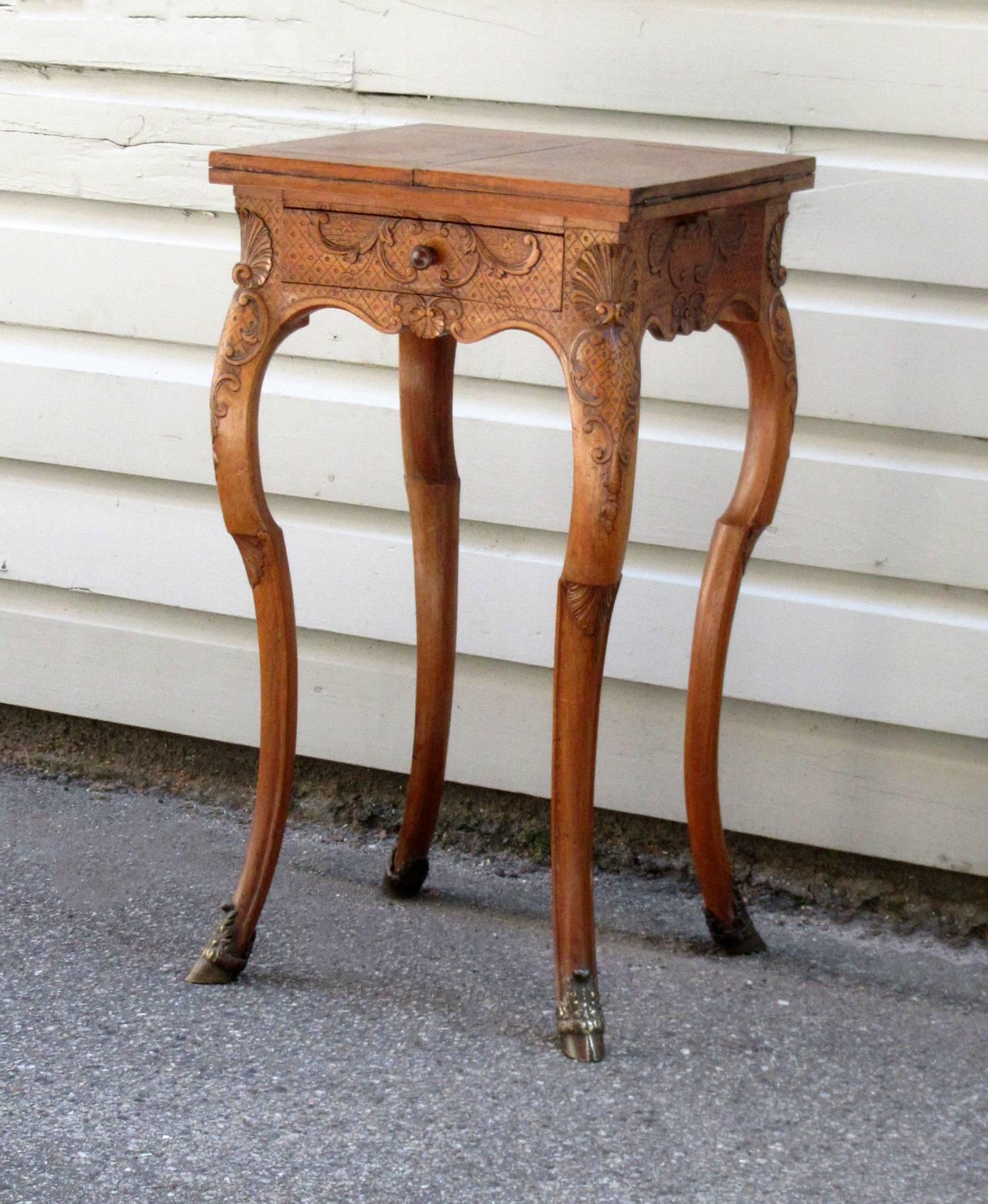 A mid-19th century French Rococo walnut game or work table, circa 1850, featuring one drawer, fine shell motif carvings and horse legs ending in bronze hoof feet. The top when opened up measures 30