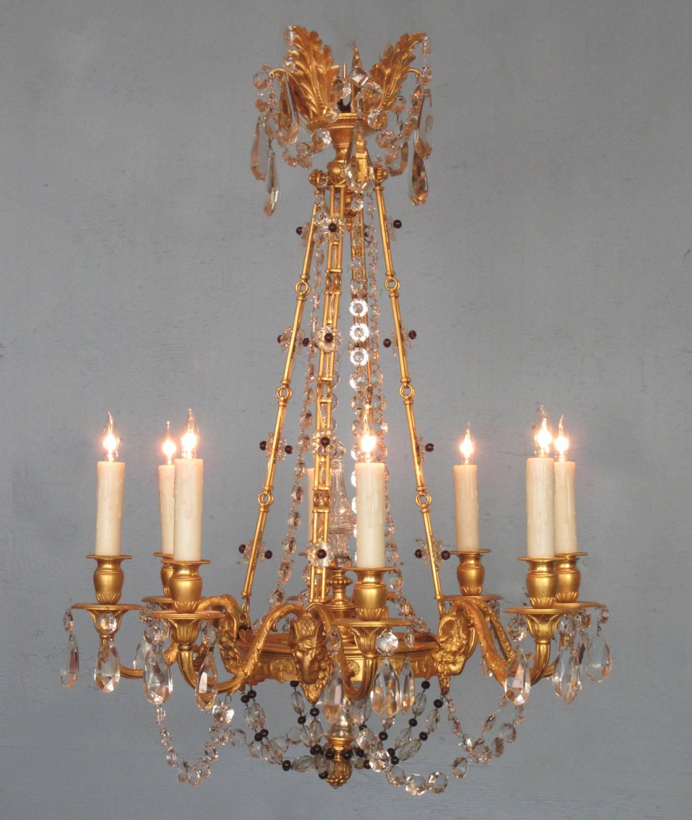 An early 20th century French Louis XIV style bronze doré chandelier, circa 1920, featuring a superbly cast bronze doré frame adorned with ram's heads and eight candle arms draped with clear cut crystal and polished amethyst beads. The chandelier was