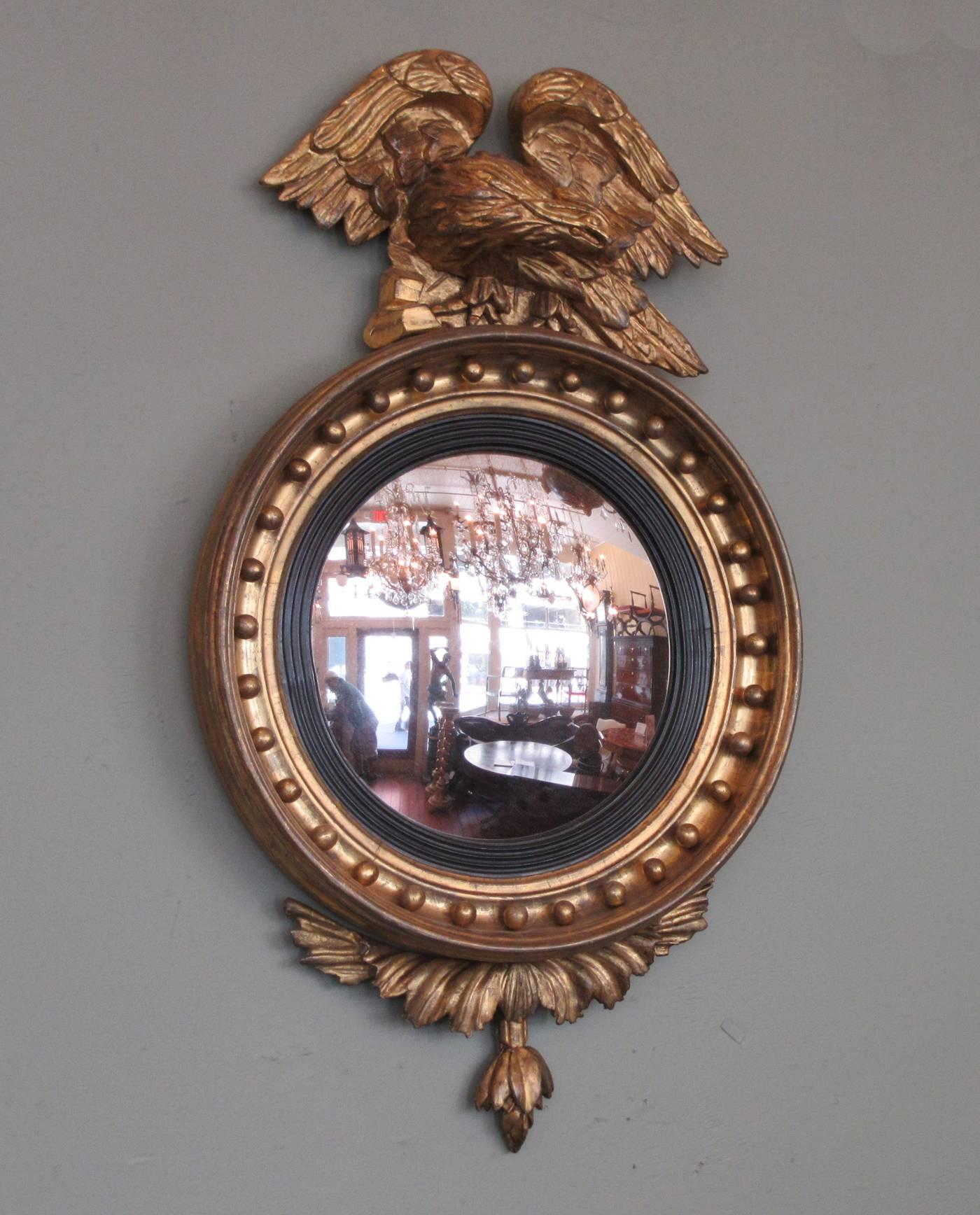 An early 19th century English Regency giltwood convex mirror, circa 1800, featuring displayed eagle, gilt balls and foliate carvings. The mirror is labeled by maker Thomas Fentham and retains its original convex mirror.  Thomas Fentham was a