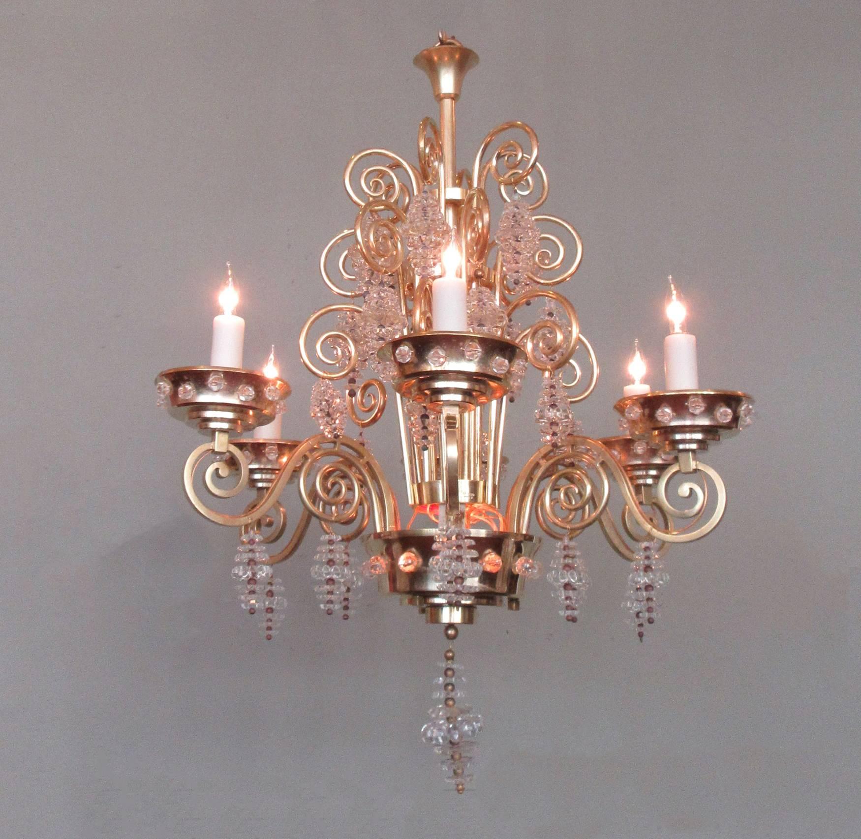 An early 20th century French Art Deco bronze chandelier, circa 1920, by famous glass artist and chandelier maker Marius-Ernst Sabino. The chandelier features six swirling bronze arms with large tiered bronze bobeches adorned with glass beads and is