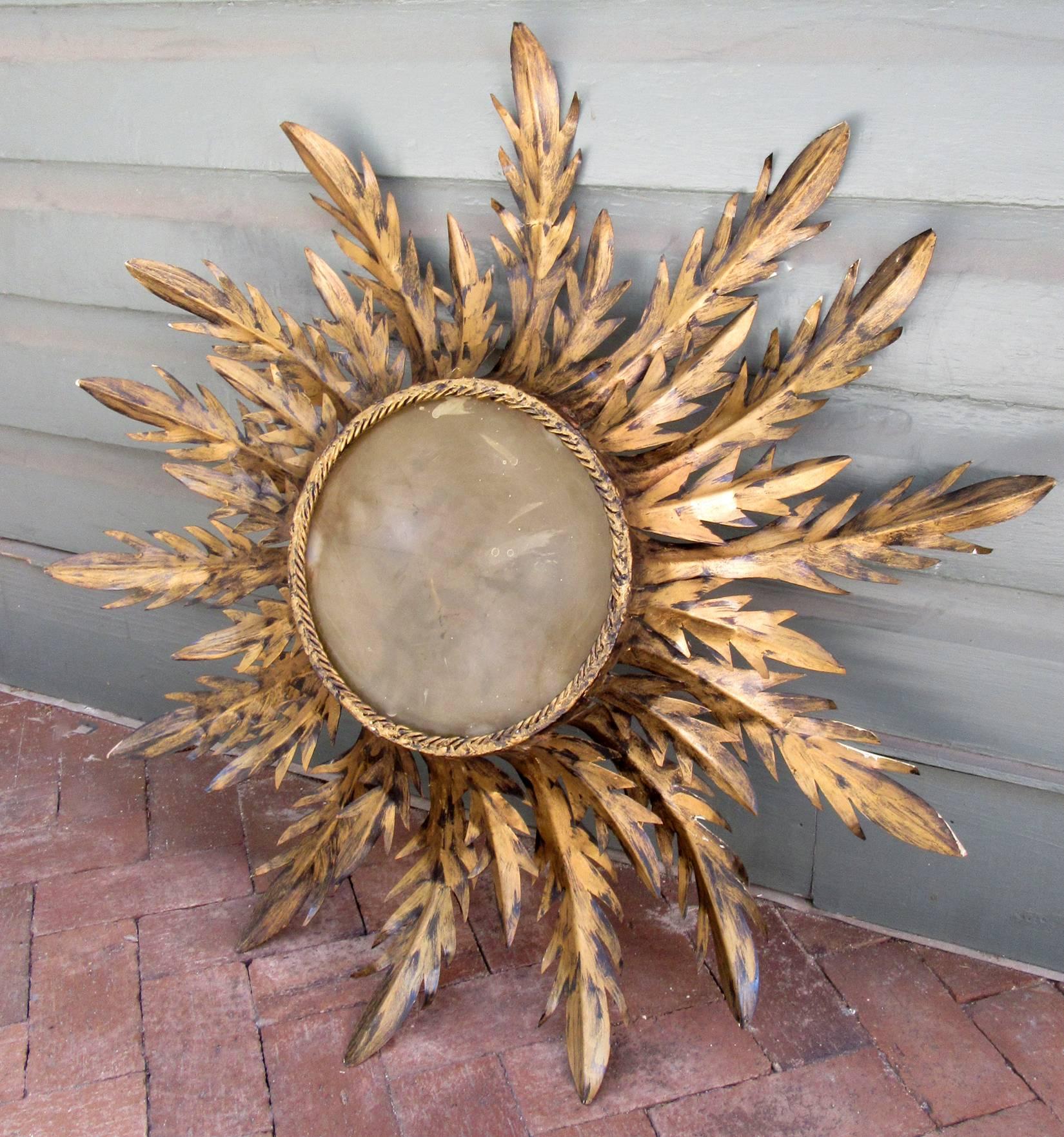 A large, free-form early 20th century Spanish Barcelona style sunburst flush mount fixture, circa 1920, with displayed gilt tole palm fronds and smoked glass insert.