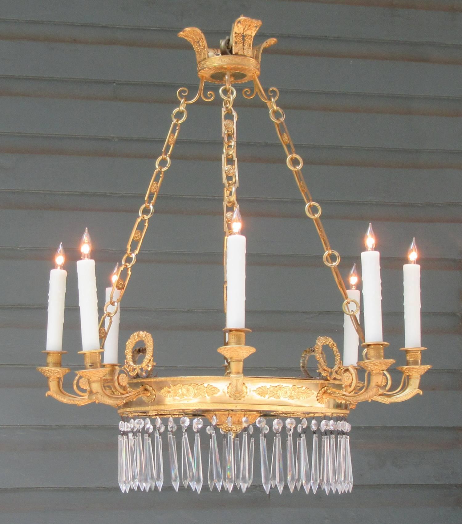 An early 19th century French Directoire bronze doré, mirror and crystal chandelier, circa 1800, featuring eight finely cast candle arms adorned with foliate and fish scale bobeche. The corona features grapes with leaves and the body of the