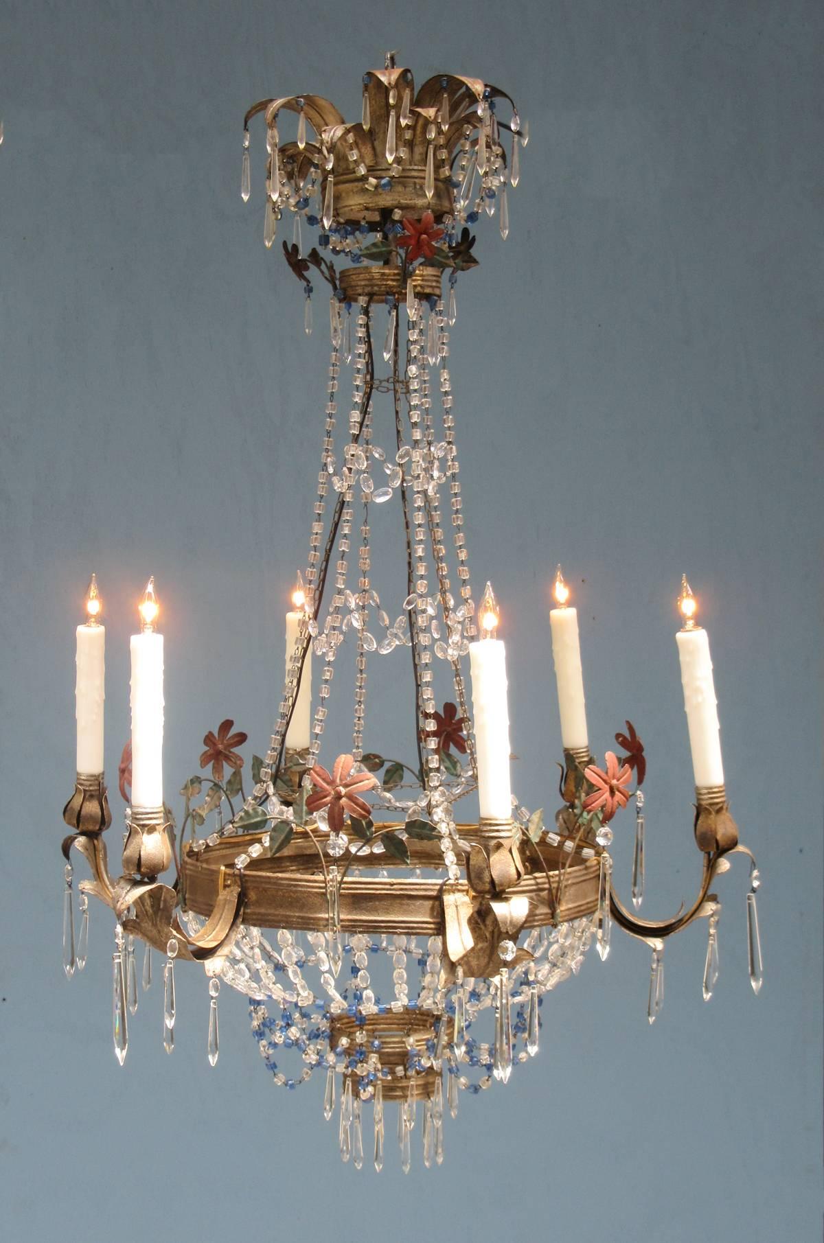 A mid-19th century Italian Empire tole and crystal chandelier, circa 1860, featuring six candle arms, painted tole floral appliques and draped with blue and white beaded crystals. The chandelier was originally candle but has recently been rewired
