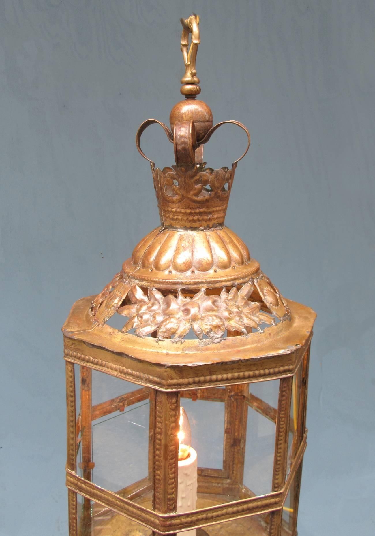 A mid-19th century Dutch Colonial brass and glass lantern from the Netherlands, circa 1850, with crown and stamped collar with pattern featuring sun and fruit motifs. The lantern has a single candle and has been recently rewired and has a new