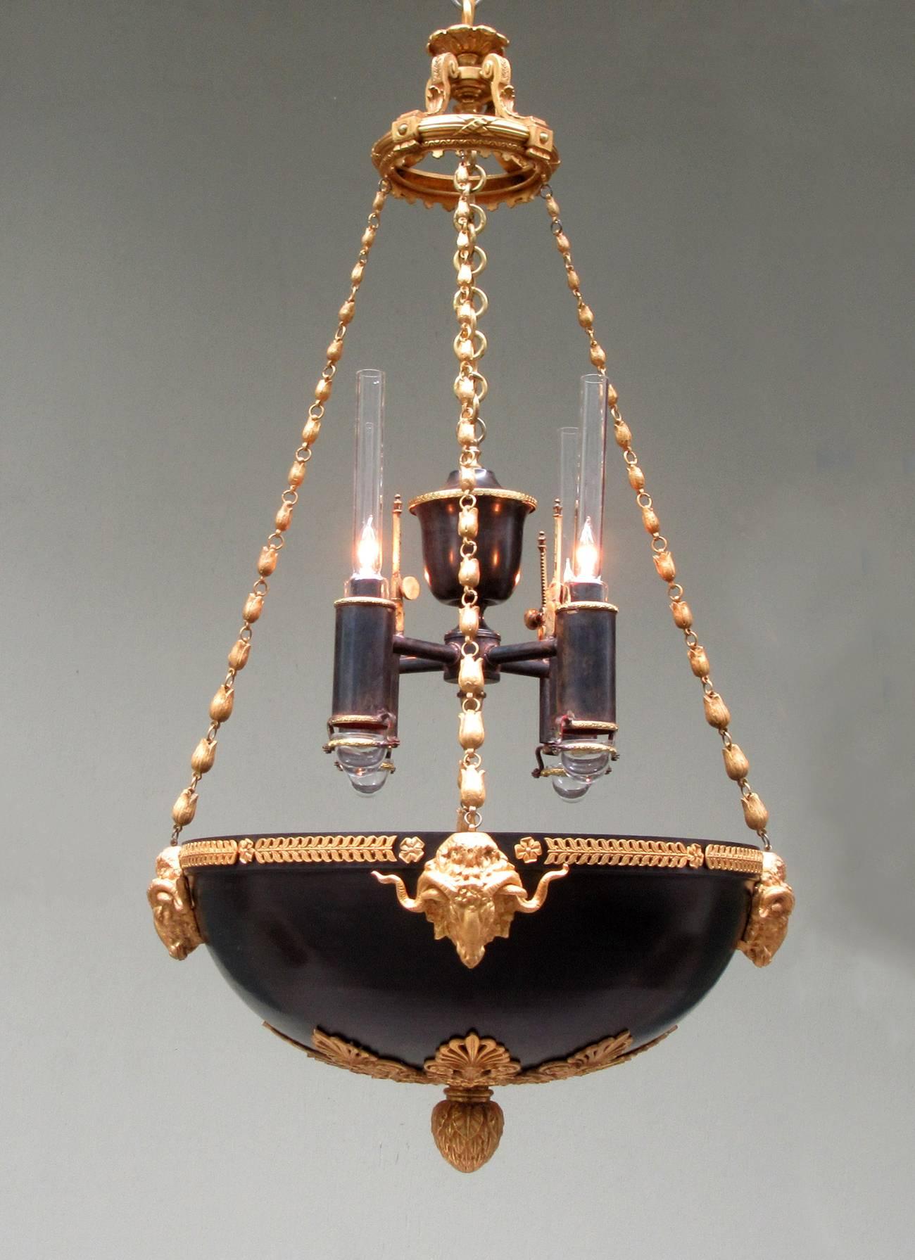 A pair of early 19th century English Regency patinated bronze and bronze doré Argand chandeliers, circa 1815, with elements of Thomas Hope such as tulip chains, anthemion and ram’s head motifs. The later added argand pendants, circa 1920, are made