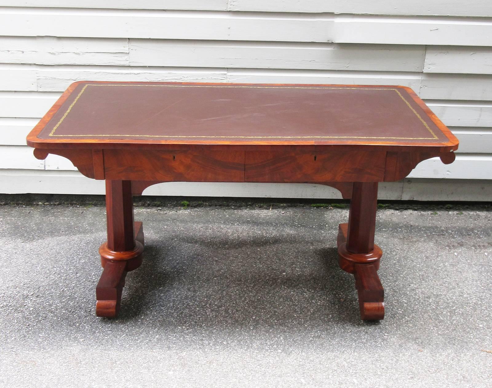 An early 19th century English Regency mahogany desk or sofa table, circa 1820, with new embossed deep brown colored leather top, two drawers and double column pedestal base.