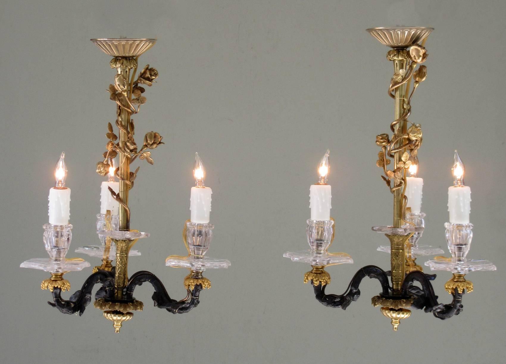 A diminutive pair of late 19th century French Louis XIV patinated bronze and bronze doré chandeliers, circa 1880, with polished rock crystal candle holders with bobeche. The chandeliers have been rewired with new porcelain sockets.