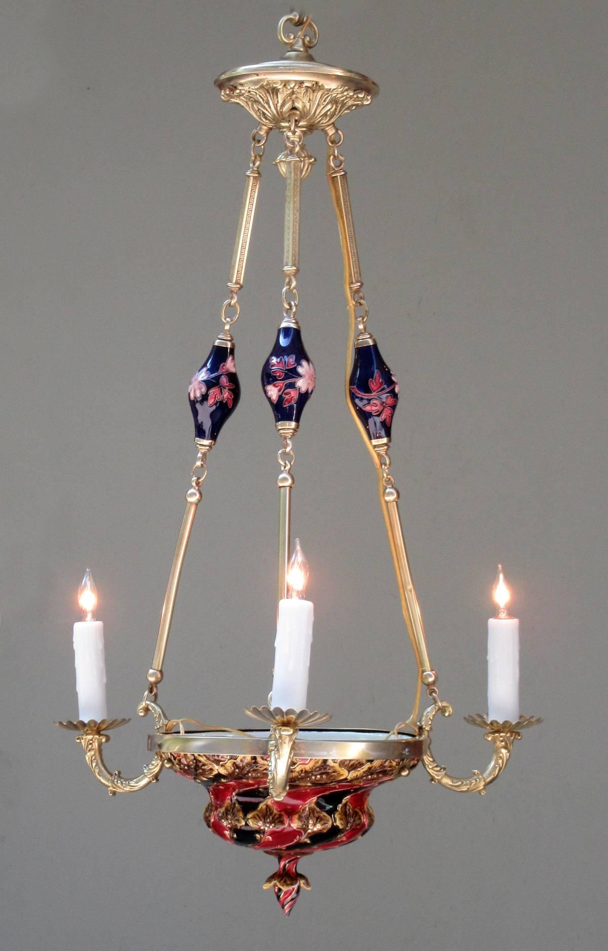 An early 20th century Bohemia (now Czech Republic) Art Nouveau Majolica and bronze chandelier, circa 1900, stamped with mark of ceramics maker Julius Biela Dressler. The chandelier is suspended by a bronze canopy with three rods accented with floral