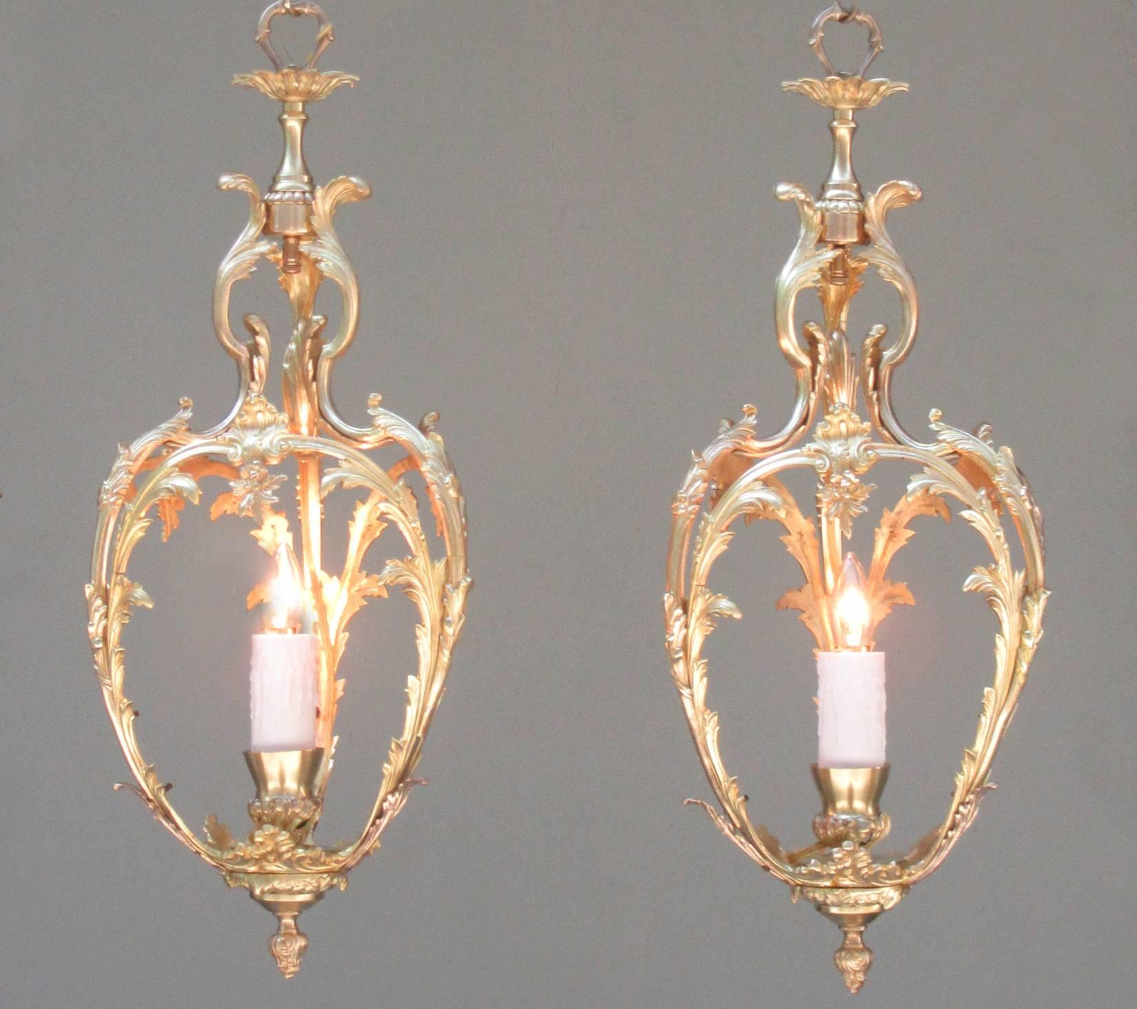 A pair of early 20th century French Louis XVI style bronze doré lanterns, circa 1910, featuring foliate castings and one candle bulb. There are two available; however, they may be purchased individually. They have recently been cleaned and rewired