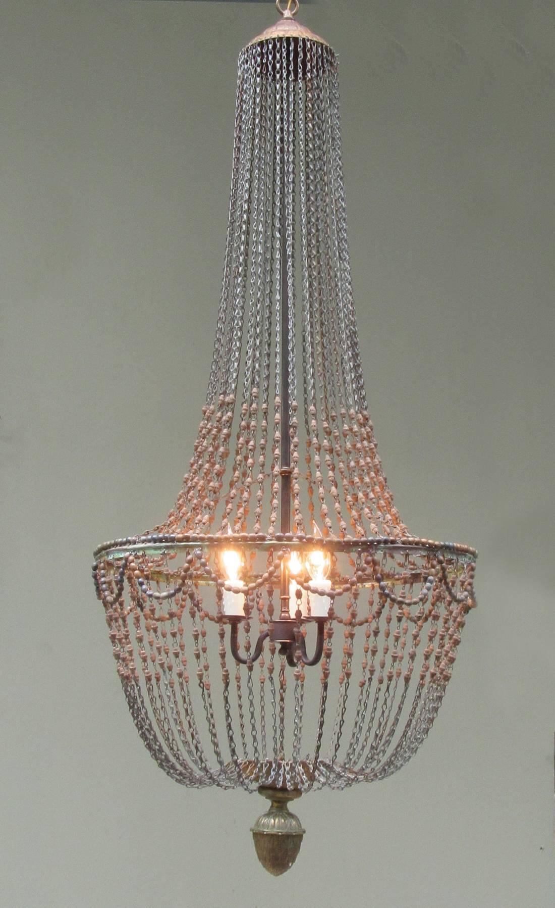 A tall early 20th century Italian Empire basket chandelier, circa 1900, featuring hand-carved wooden beads, three candle bulb pendant drop and finely detailed brass pine cone finial. The chandelier has recently been cleaned and rewired with new