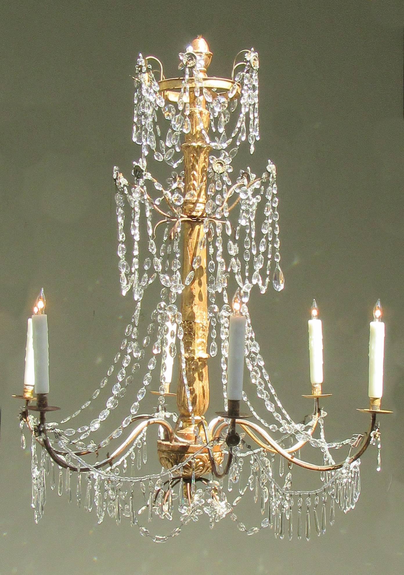A late 18th century Italian Genoese giltwood, tole and crystal chandelier, circa 1780, with hand-carved stem and six candle arms draped with cut crystal pendants.
