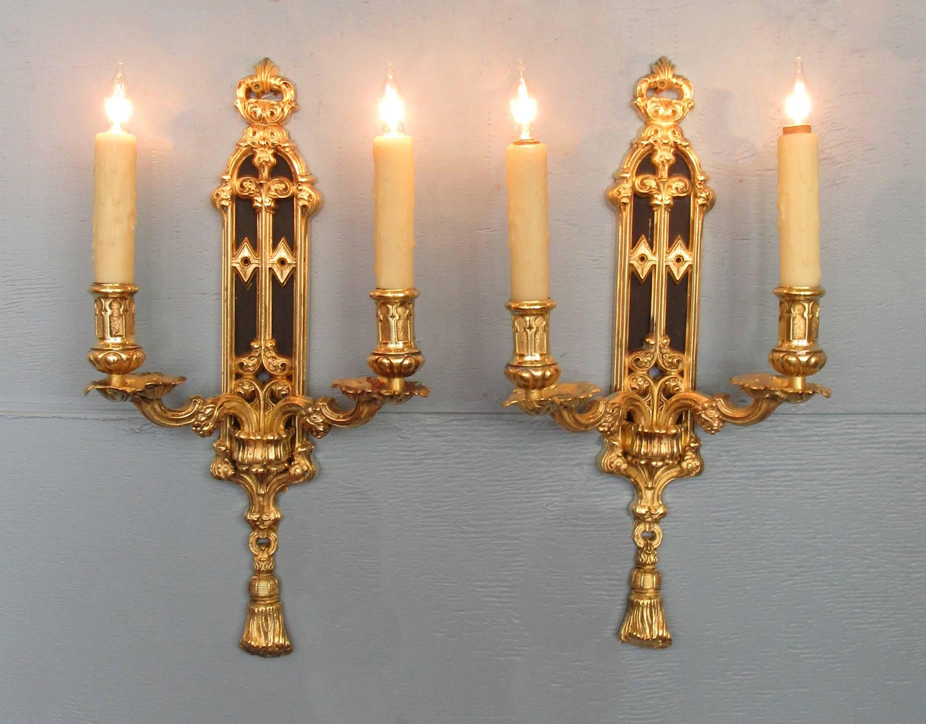 A pair of finely cast English Gothic bronze dore and patinated sconces, circa 1840,  each with two candle arms.  The sconces were originally gas but have been recently cleaned and rewired with new porcelain sockets.