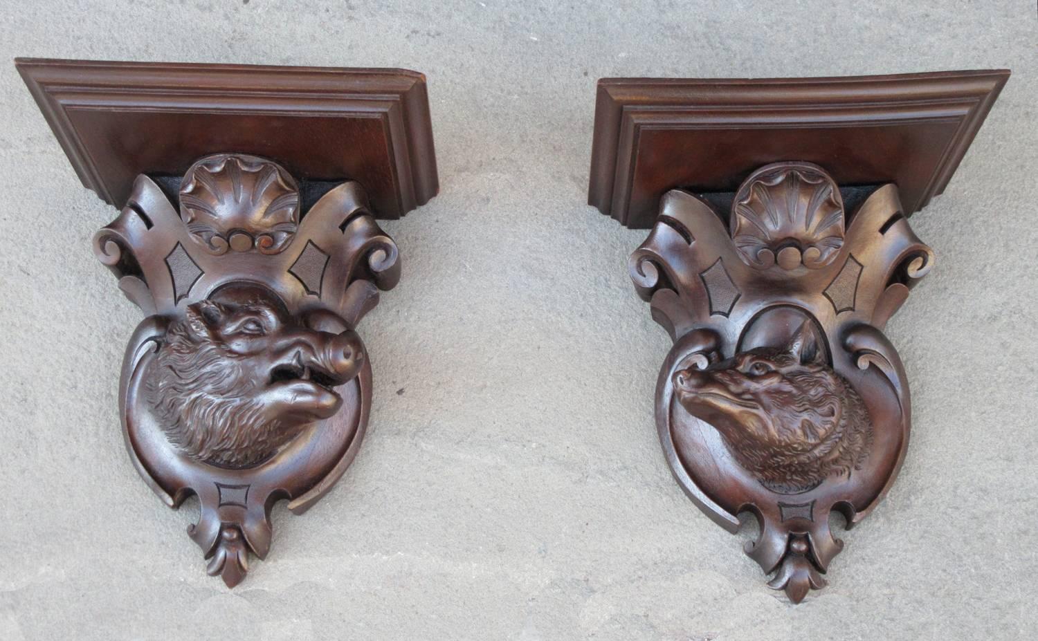 A handsome pair of carved walnut German Black Forest wall brackets, circa 1880, featuring opposing boar and fox head cartouche.