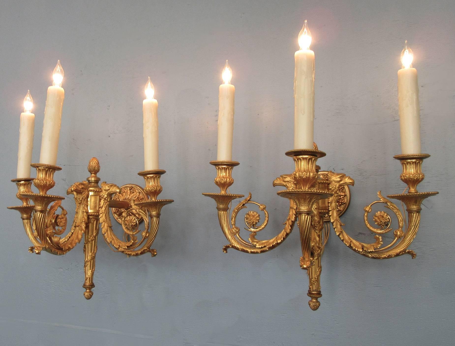 A large pair of exceptionally well cast 19th century French Empire bronze doré sconces, circa 1810, featuring quiver base with three candle arms, finely detailed eagle heads, foliate and grape motifs.