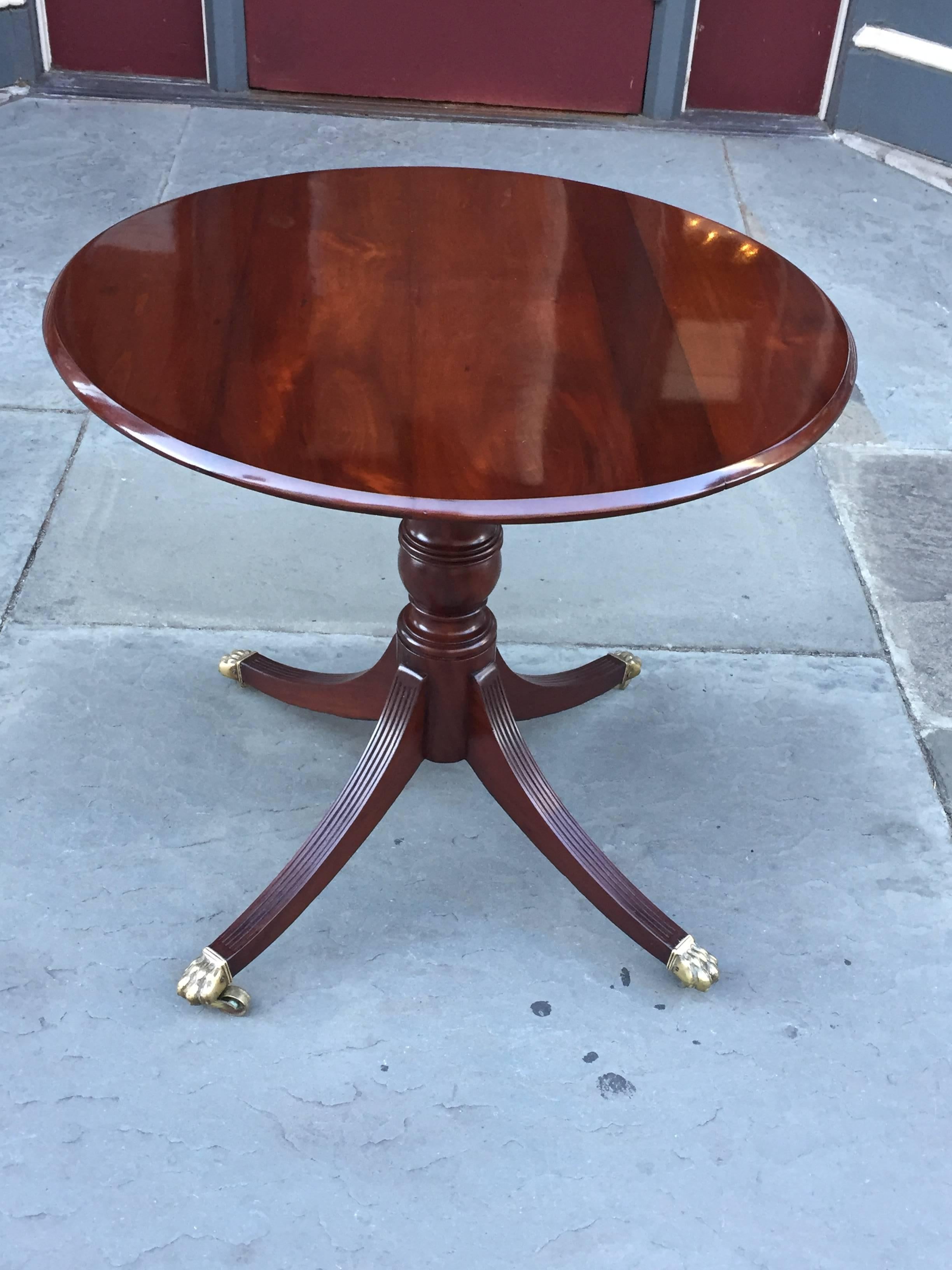 A tilt-top tea table from Barbados that sits on a urn-shaped pedestal with four, reeded sabre legs ending in brass claw toes, circa 1810.