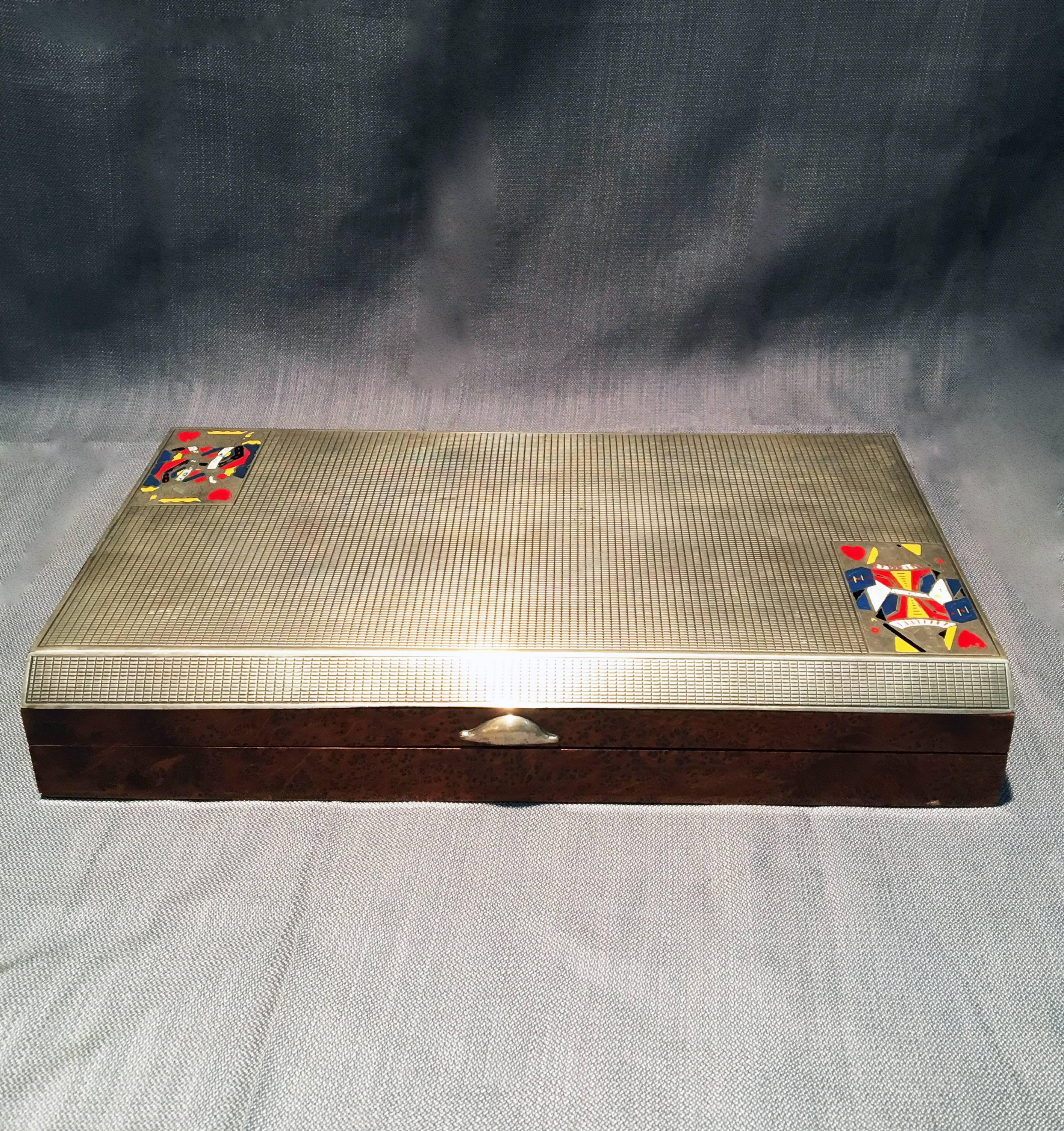 This 1920's 800 silver and walnut game case featuring the king and queen of hearts comes with playing cards, chips, and dominoes. The case has been stamped with a hallmark. 