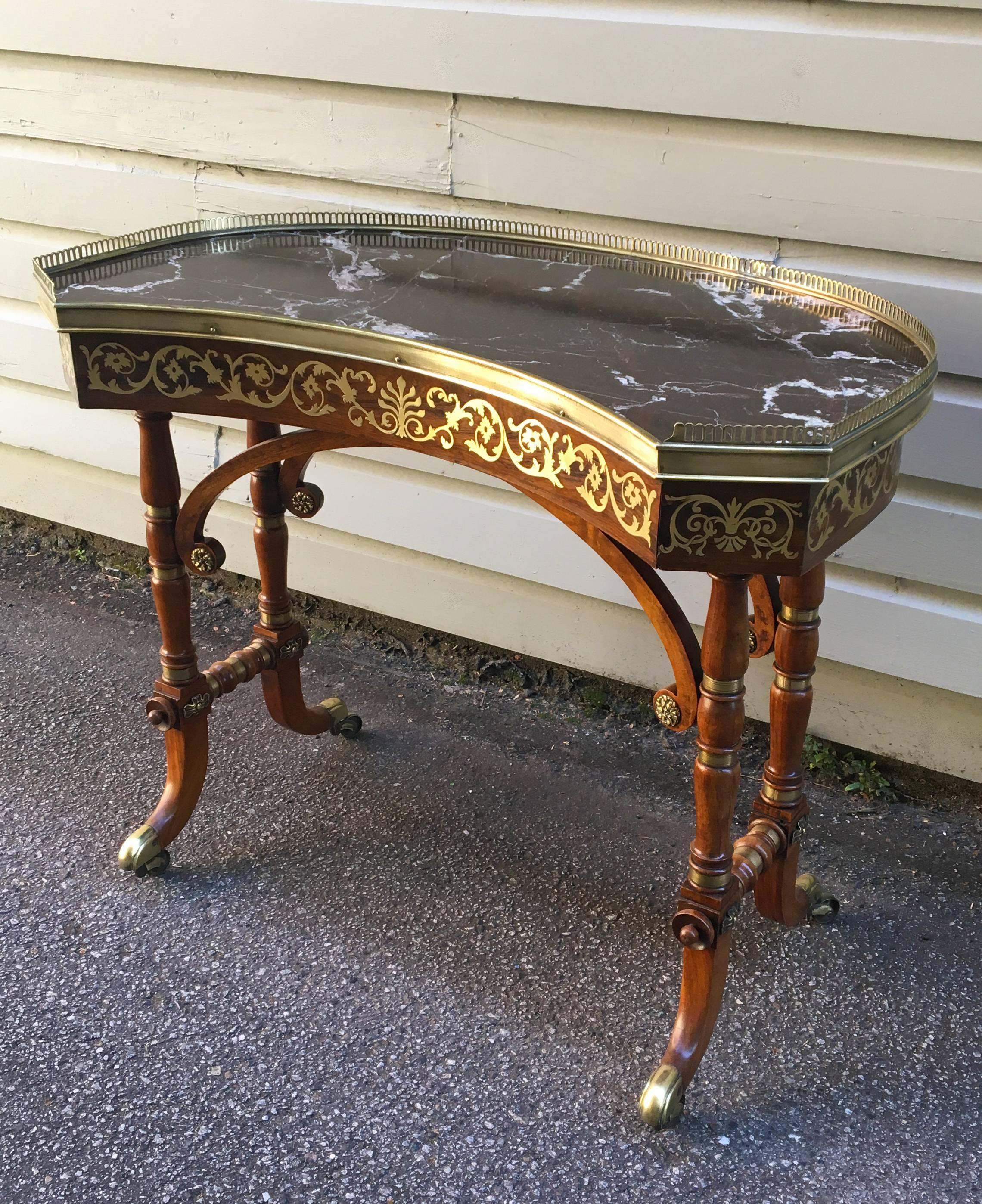 An early 19th century English Regency rosewood library/dressing table attributed to John McLean. This table is kidney shaped with floral designed inlaid brass (Boulle inlay). Marble top surrounded by cast brass gallery. Beautiful trestle base with