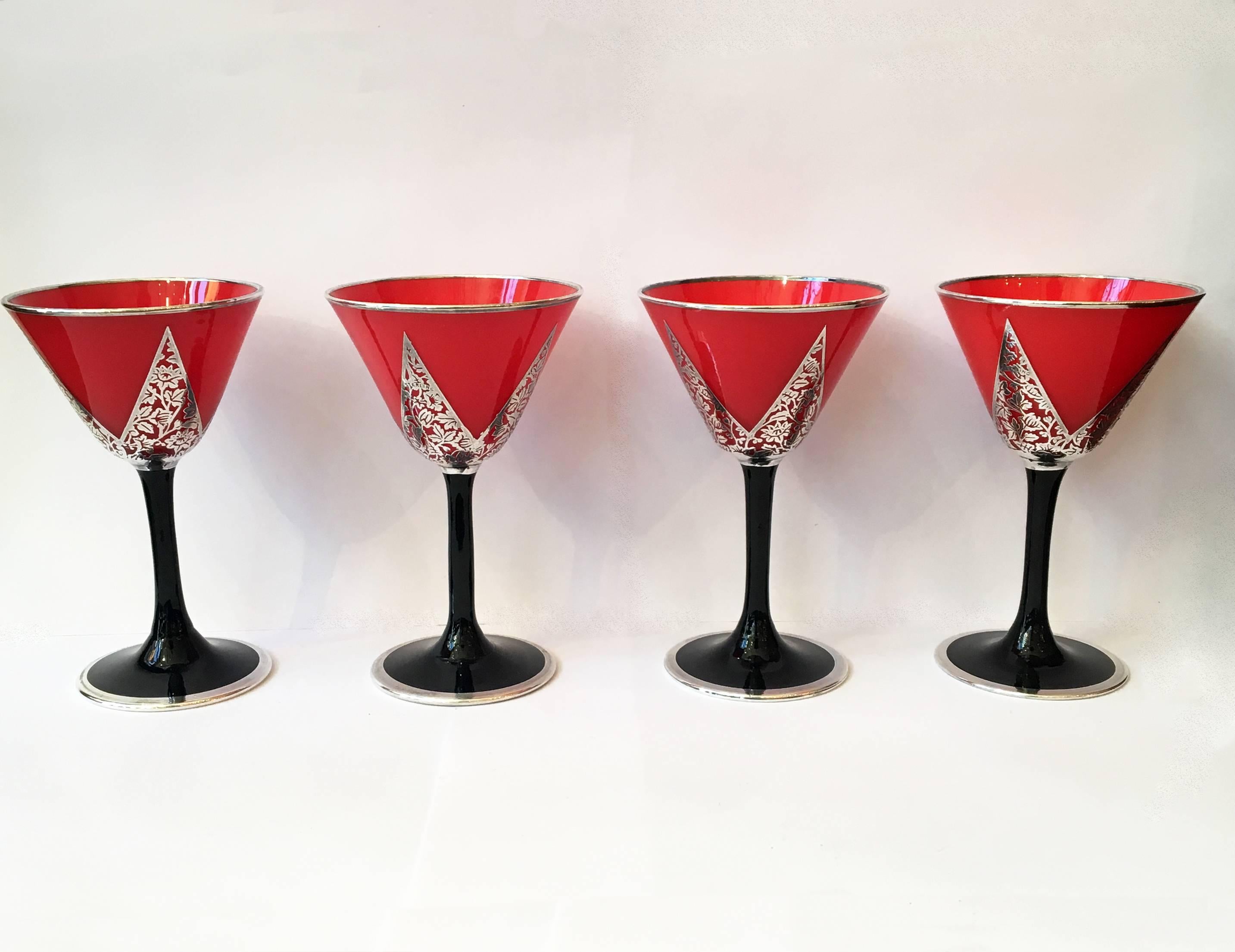 These early 20th century Art Deco cocktail glasses come in a set of four. The unique blood orange glass is decorated with beautiful sterling silver overlay. The stem of the glassware is black with silver lining the edge of the base.