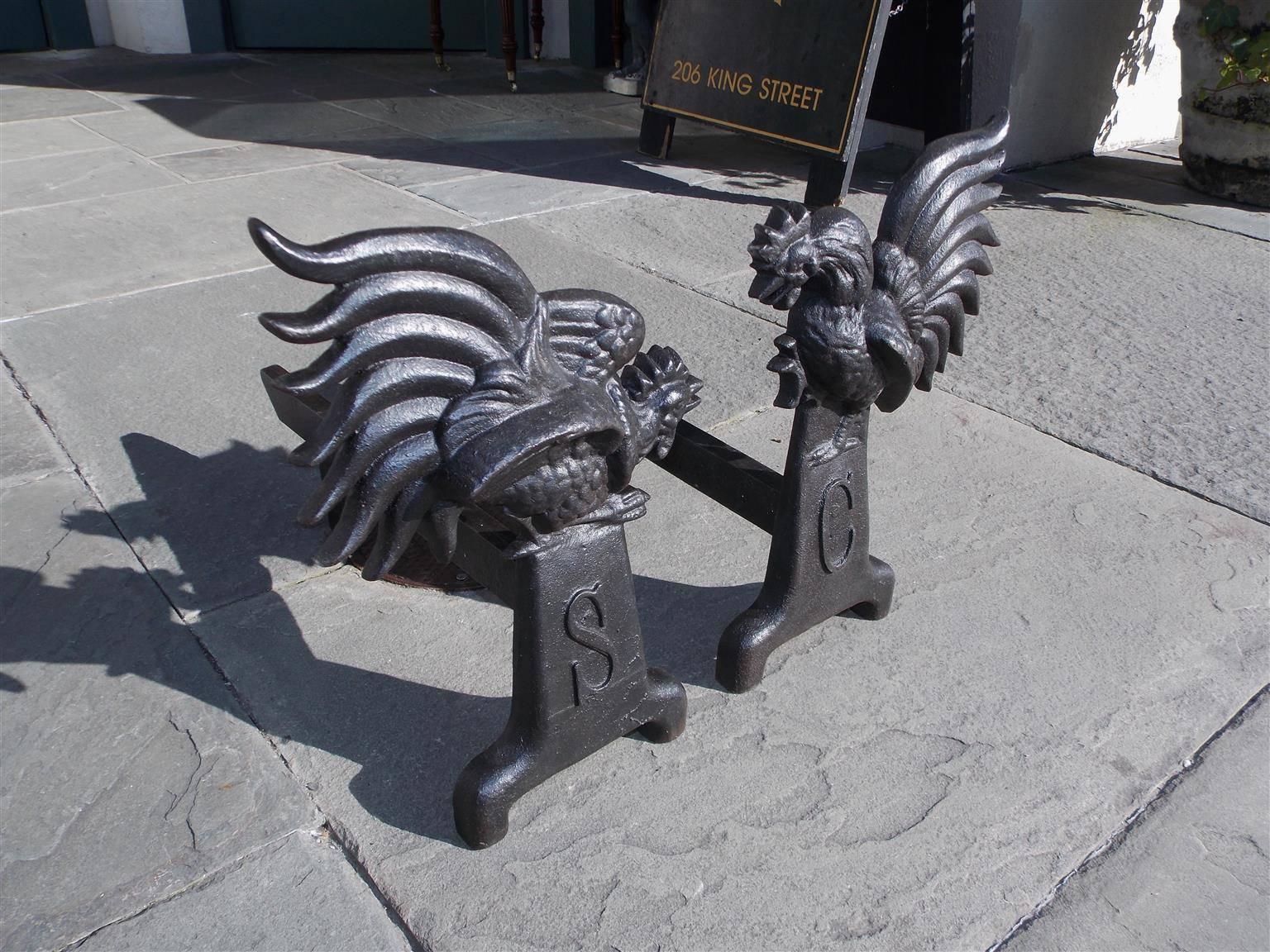 Pair of American cast iron fighting gamecock andirons with rectangular plinths stamped SC, original dog legs, and terminating on scrolled block legs. Mid-19th Century. South Carolina.