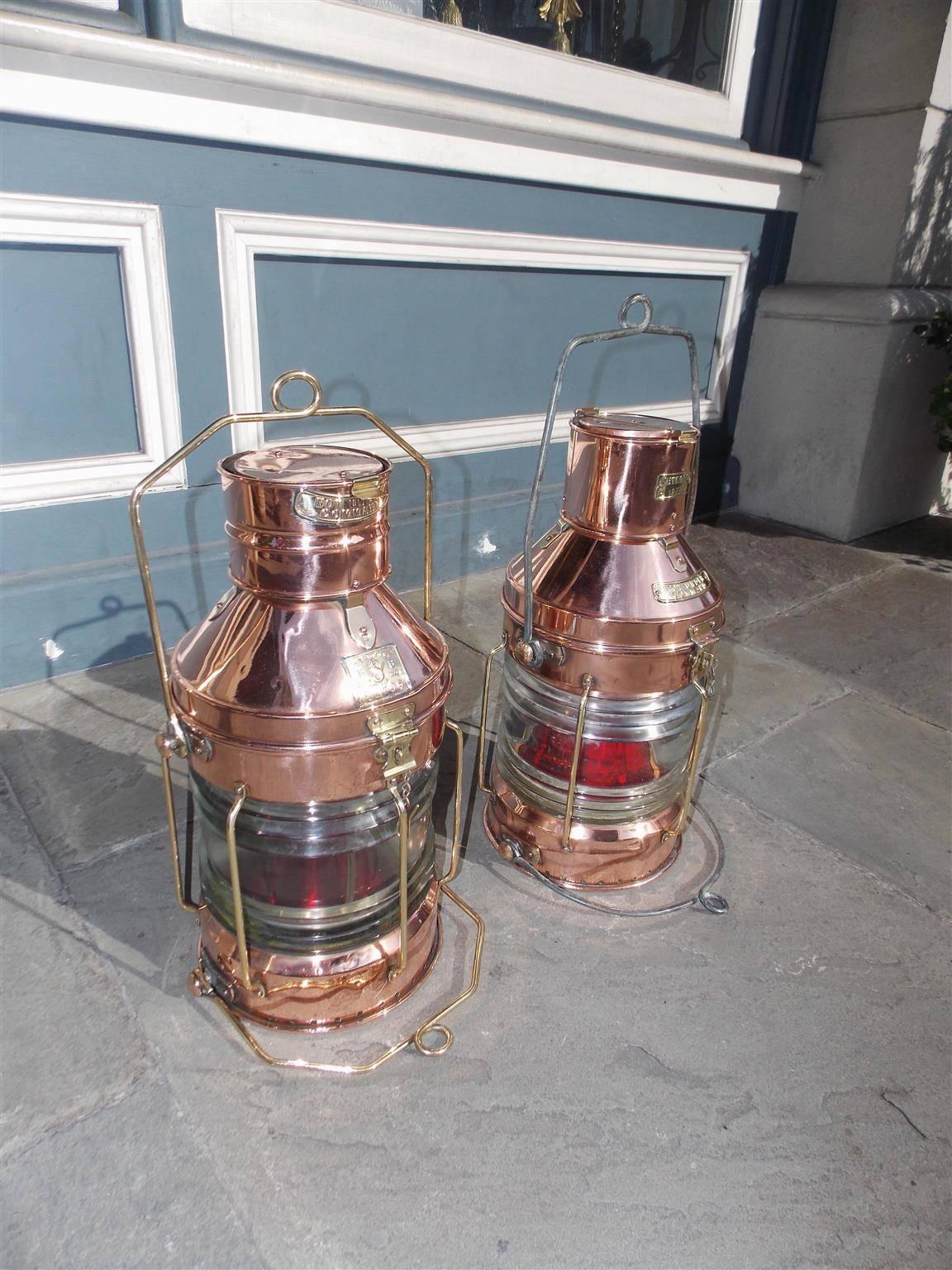 Pair of English copper and brass nautical ship lanterns with original Fresnel lenses, brass and steel carrying handles, vented tops, and makers badge, Early 20th Century.