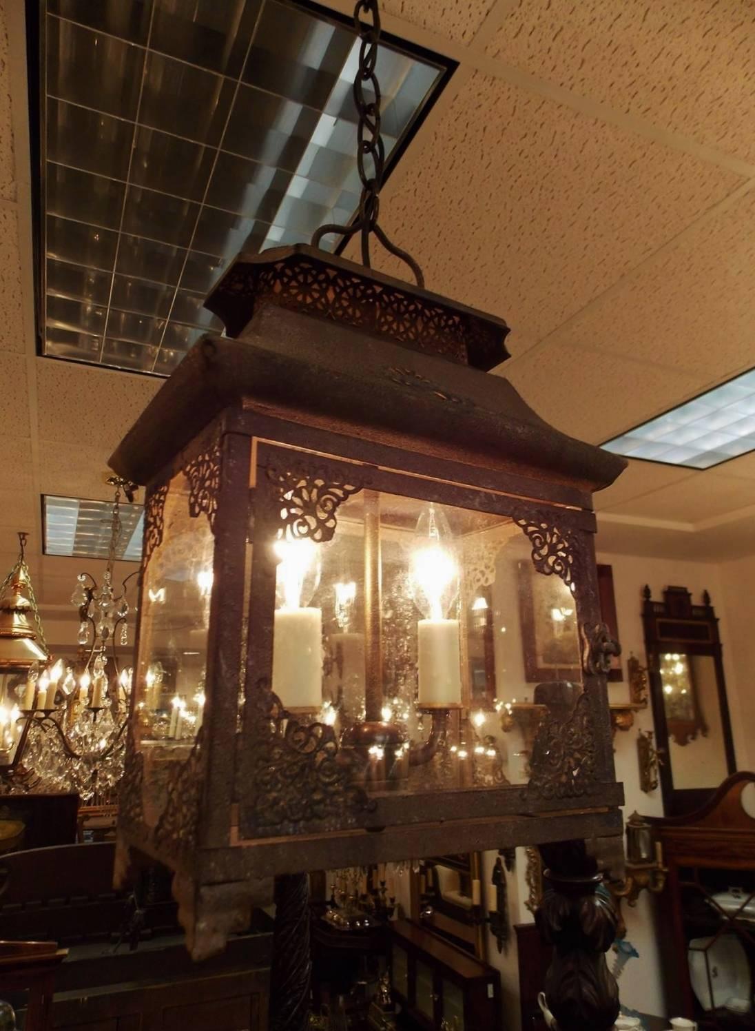 English tin rectangular pagoda hanging lantern with a centered handle, filigree molded Pagoda top, four glass sides with corner filigree and a hinged door, resting on corner scalloped fan feet. Lantern was originally candle powered and has been