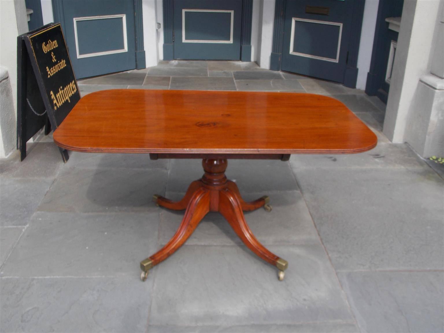 Scottish mahogany one board tilt top breakfast table with reeded molded edge, original brass locking mechanism, turned bulbous ringed pedestal, and resting on four reeded saber legs with the original brass casters. Early 19th Century.