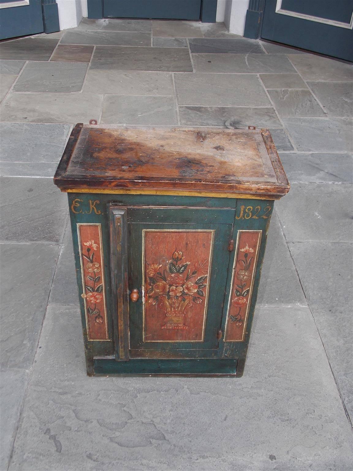 French Deil painted and stenciled exposed dovetail hanging cabinet with a hinged strap door, interior shelving, lower drawer, and decorative floral motif. Signed EK, Circa 1822.