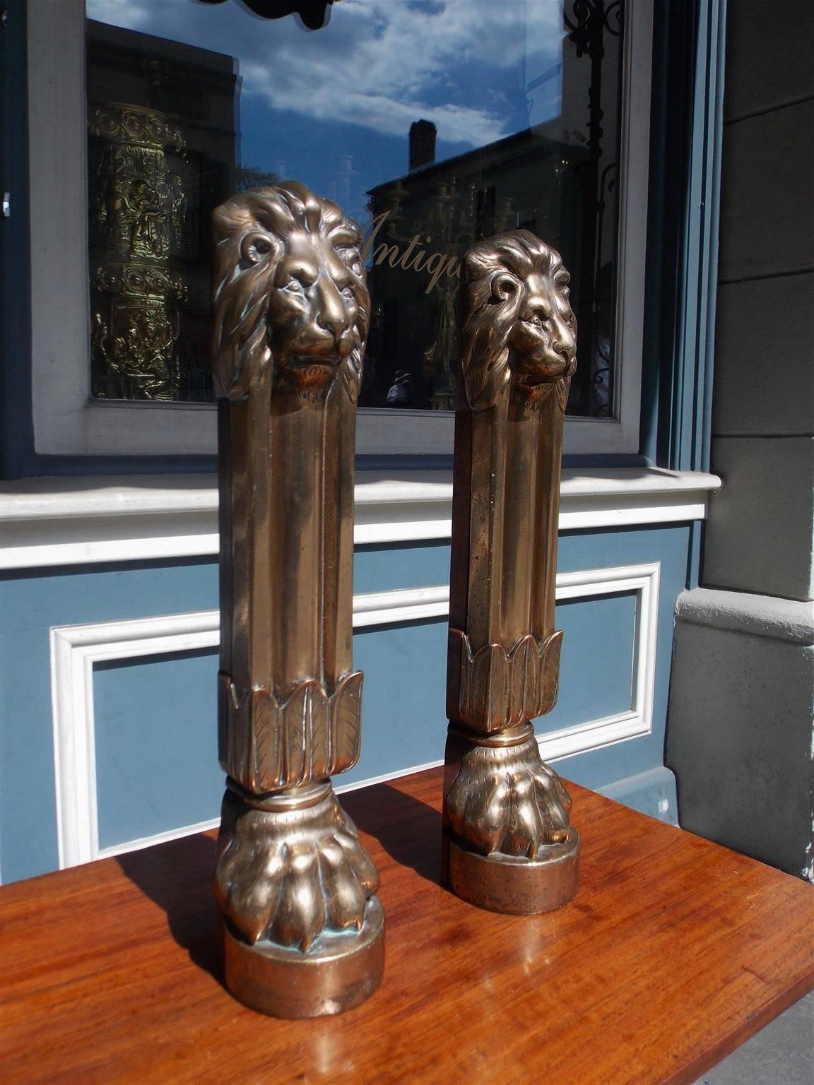 Pair of English brass and oak doorstops with flanking lions head, fluted columns, acanthus foliage and terminating on circular lions paw feet plinths, Late 18th Century.