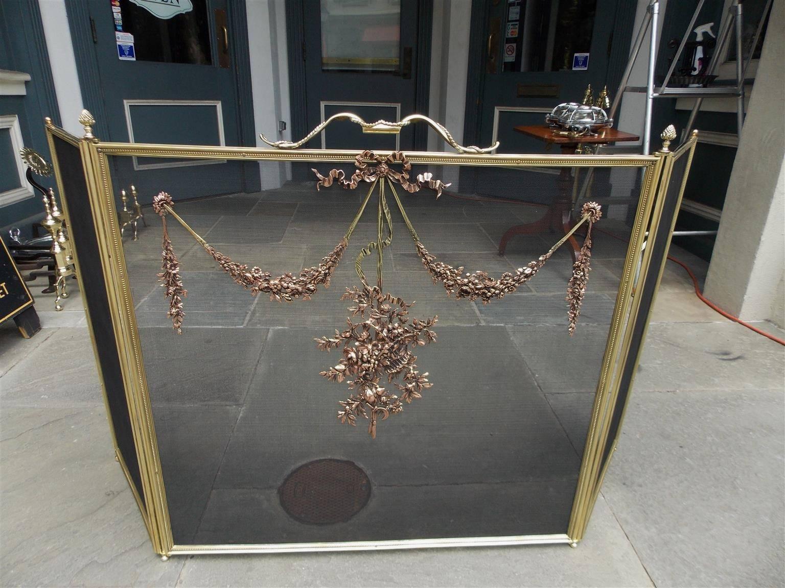 French brass and copper free standing three panel fire screen with centered floral handle, decorative ribbon motif, floral rosette swags, lower flower basket, and corner artichoke finials, Mid-19th century.  Middle screen panel is 31.5