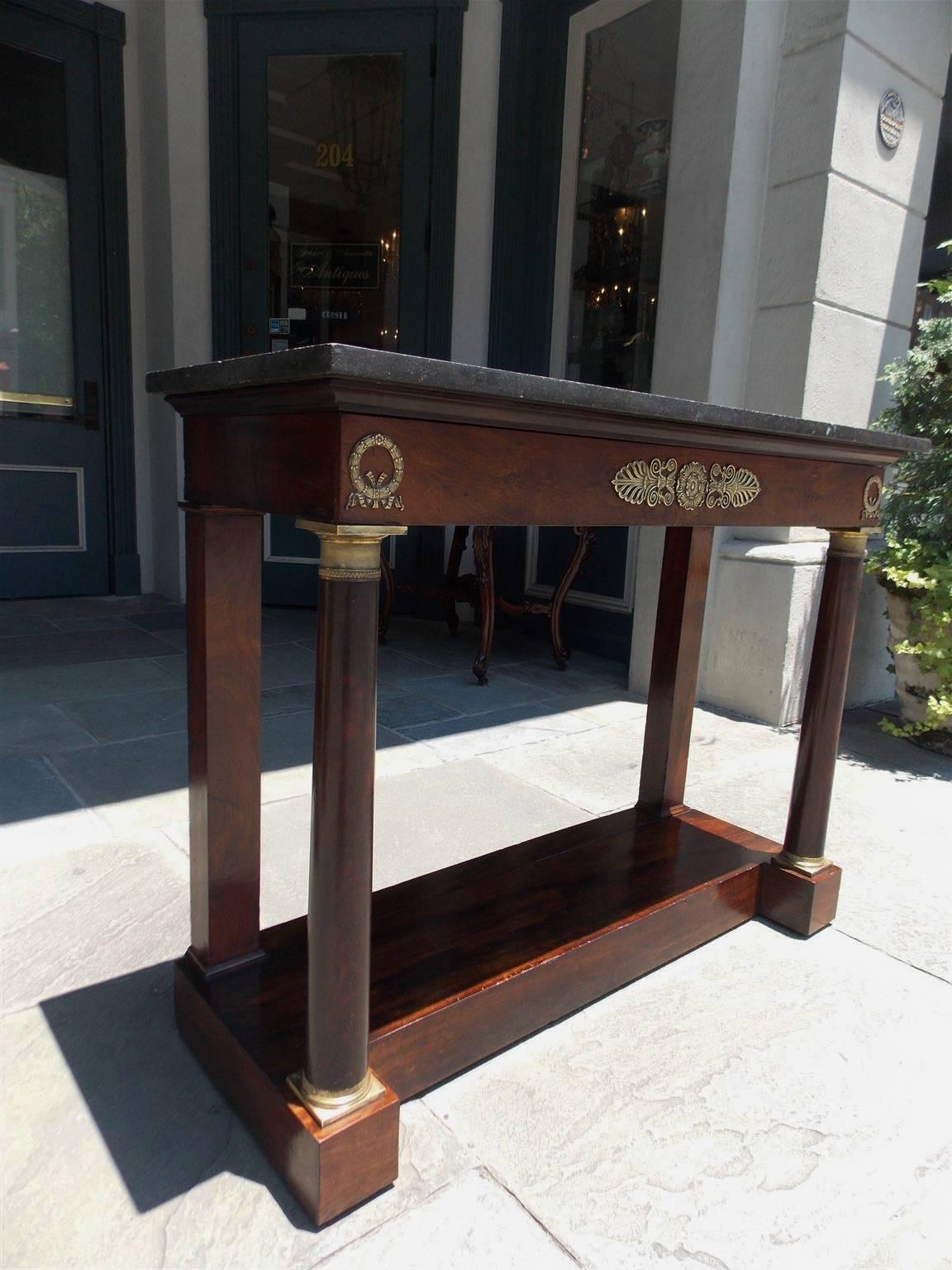 French Neoclassic mahogany compartmentalized one drawer marble-top console with flanking ormolu laurel wreath mounts, centered medallion ormolu filigree, circular columns with original bronze mounts, and resting on a raised rectangular mahogany