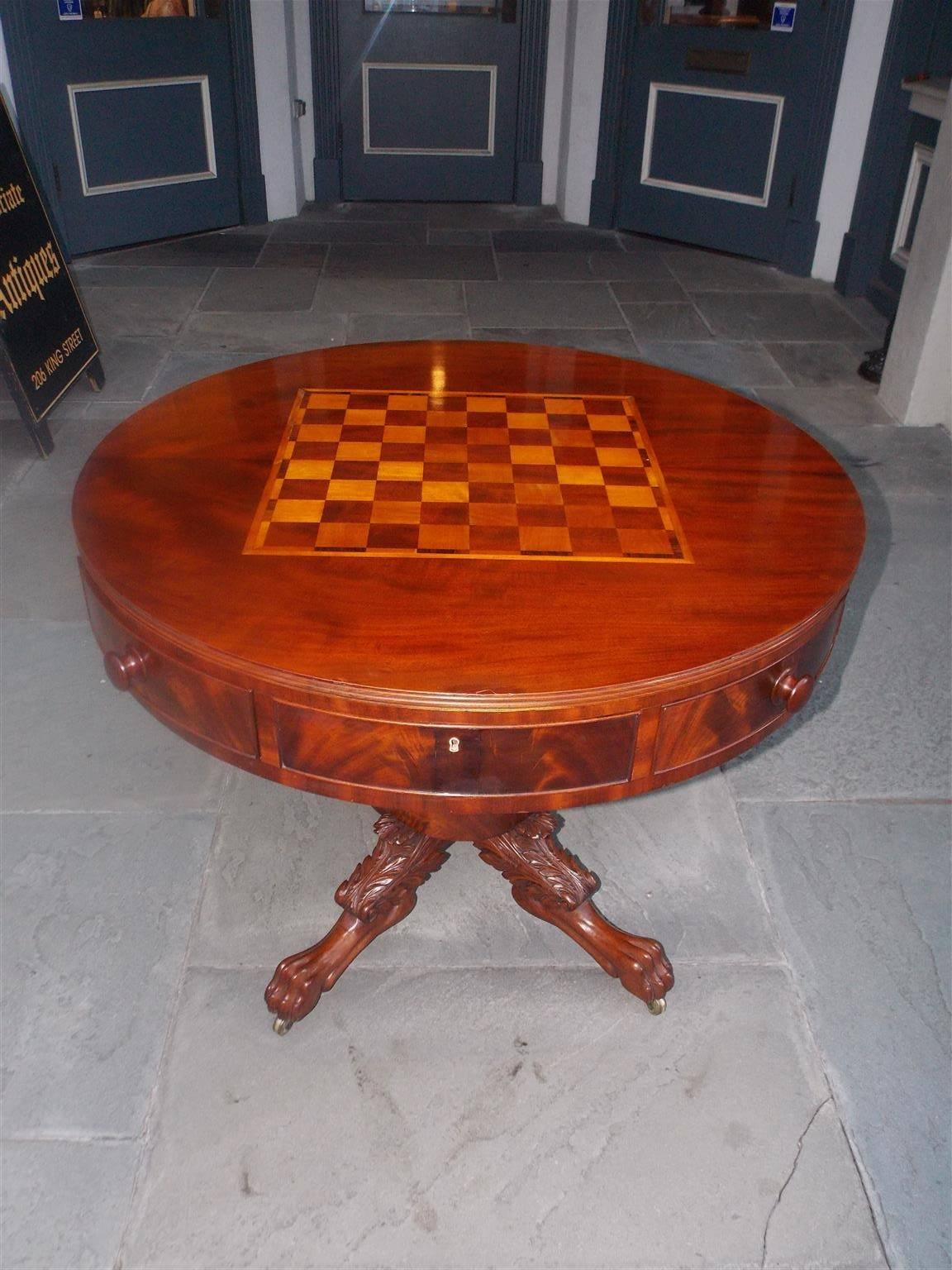 American mahogany circular game table with inlaid chess board, eight drawers with the original wooden knobs, resting on a acanthus carved bulbous pedestal with lions paw feet and original brass casters, Philadelphia, Early 19th Century.