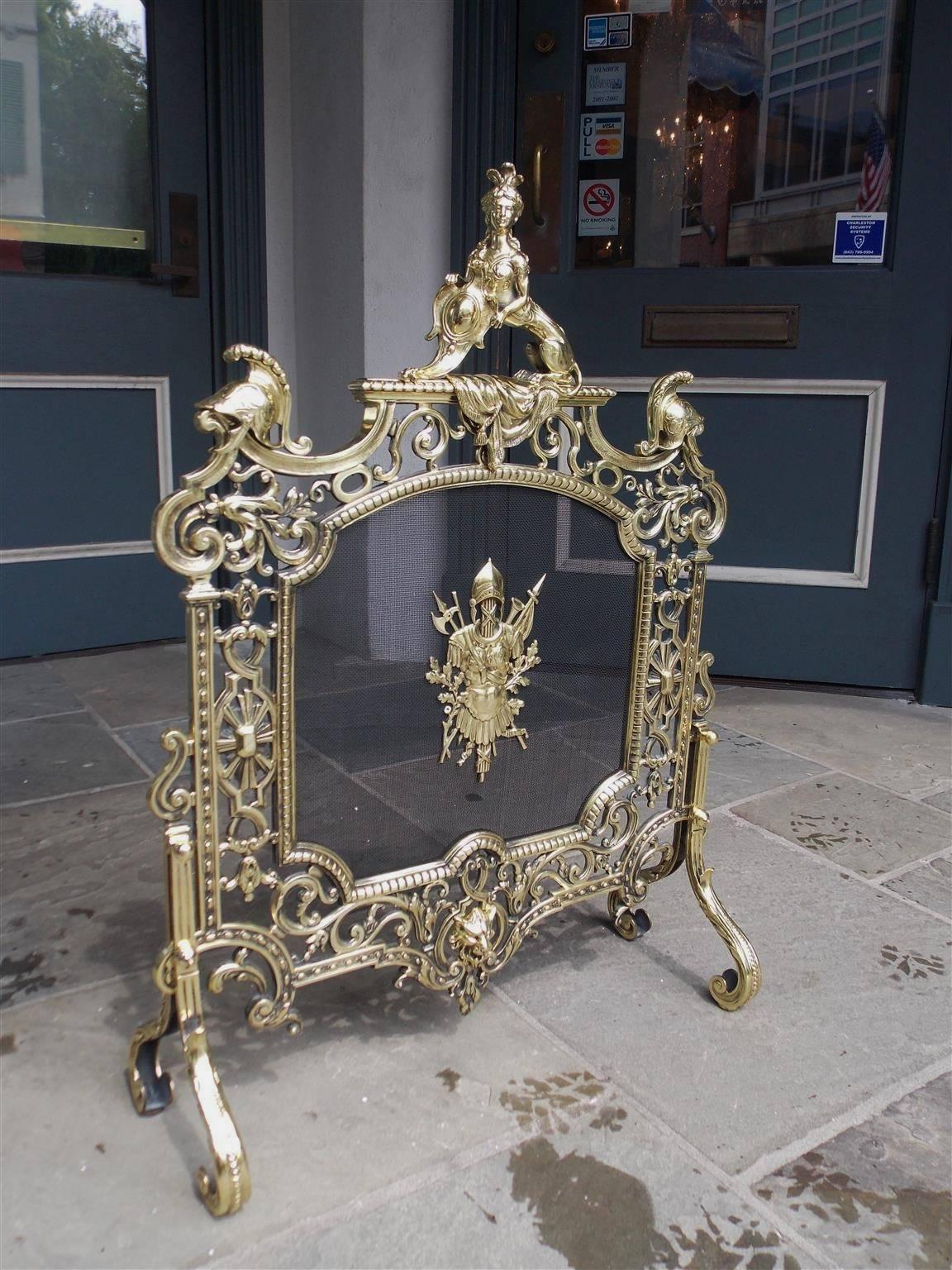 English brass Britannia free standing fire screen with centered sphinx, flanking war helmets with plumes, interior bead work, scrolled floral chasing, centered war armored medallion, lower leopard head, and resting on scrolled beaded acanthus legs,
