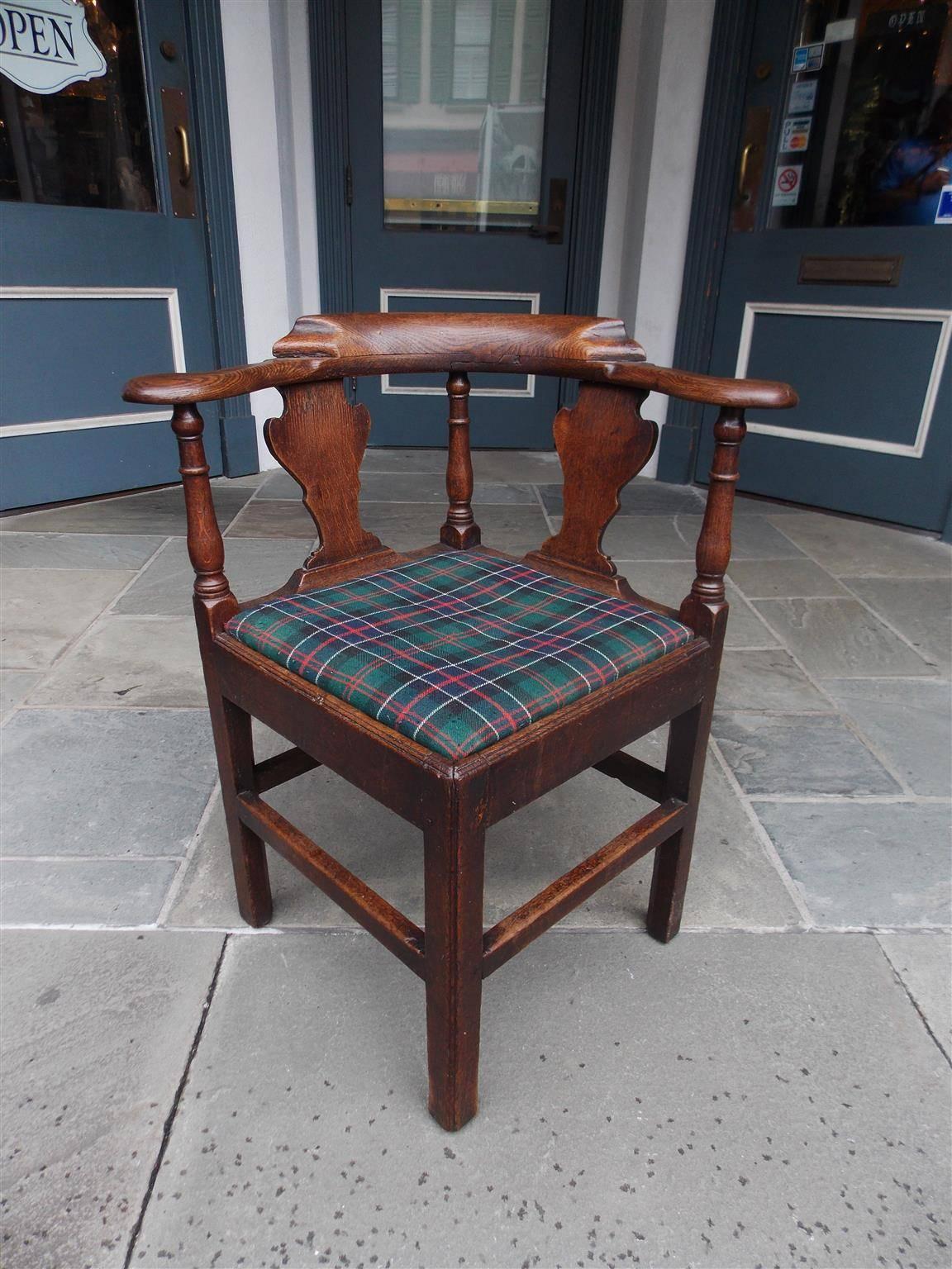 English Chippendale oak corner chair with a carved molded centered edge, flanking carved splat backs, scrolled outset rounded arms, turned bulbous ringed columns and terminating on the original squared legs with connecting stretchers. Chair has the