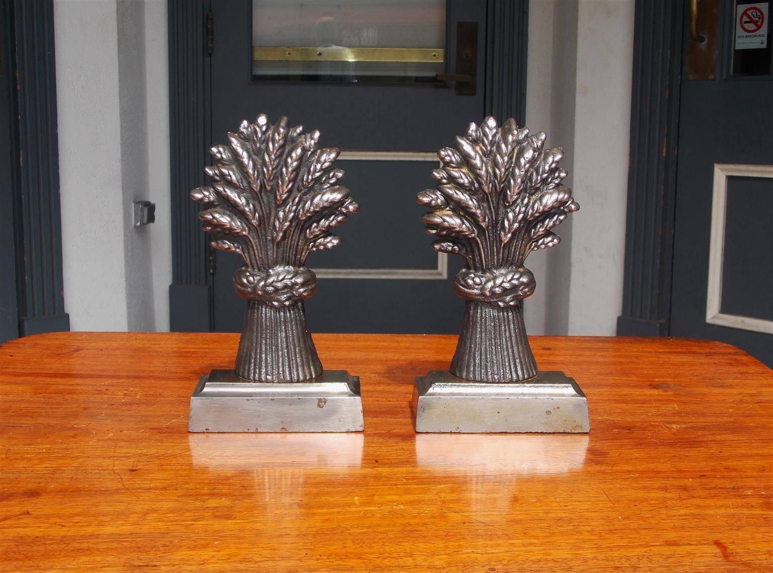 Pair of English cast polished steel wheat sheaths book ends resting on step back rectangular plinths, Early 19th Century.