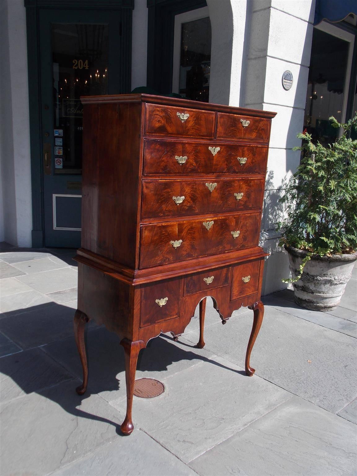 American Queen Anne walnut graduated highboy with a carved molded edge cornice, five upper case drawers, centered molded edge, three lower case drawers, original hand chased cotter pin brasses, carved scalloped skirt with coin silver banding, acorn