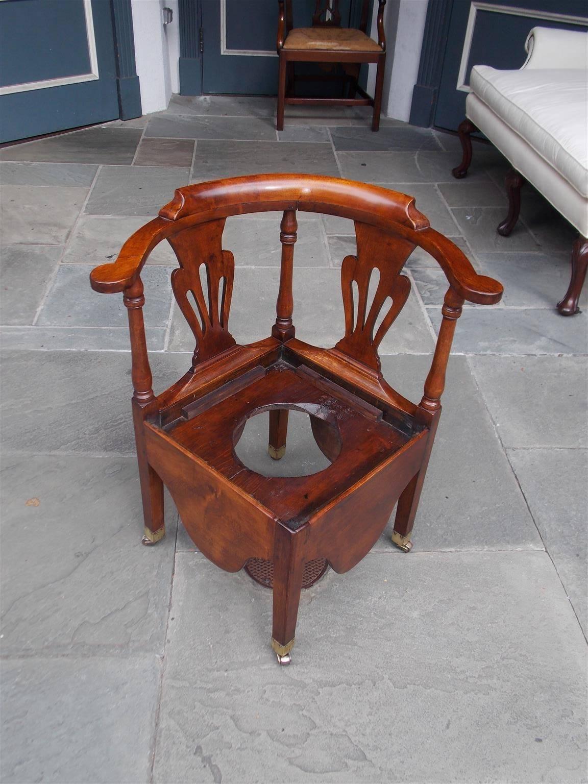 American Chippendale maple corner potty chair with carved molded scrolled arms, flanking splat backs, turned bulbous ringed columns, original wooden seat frame, carved scalloped skirts and terminating on the original squared legs with brass casters.