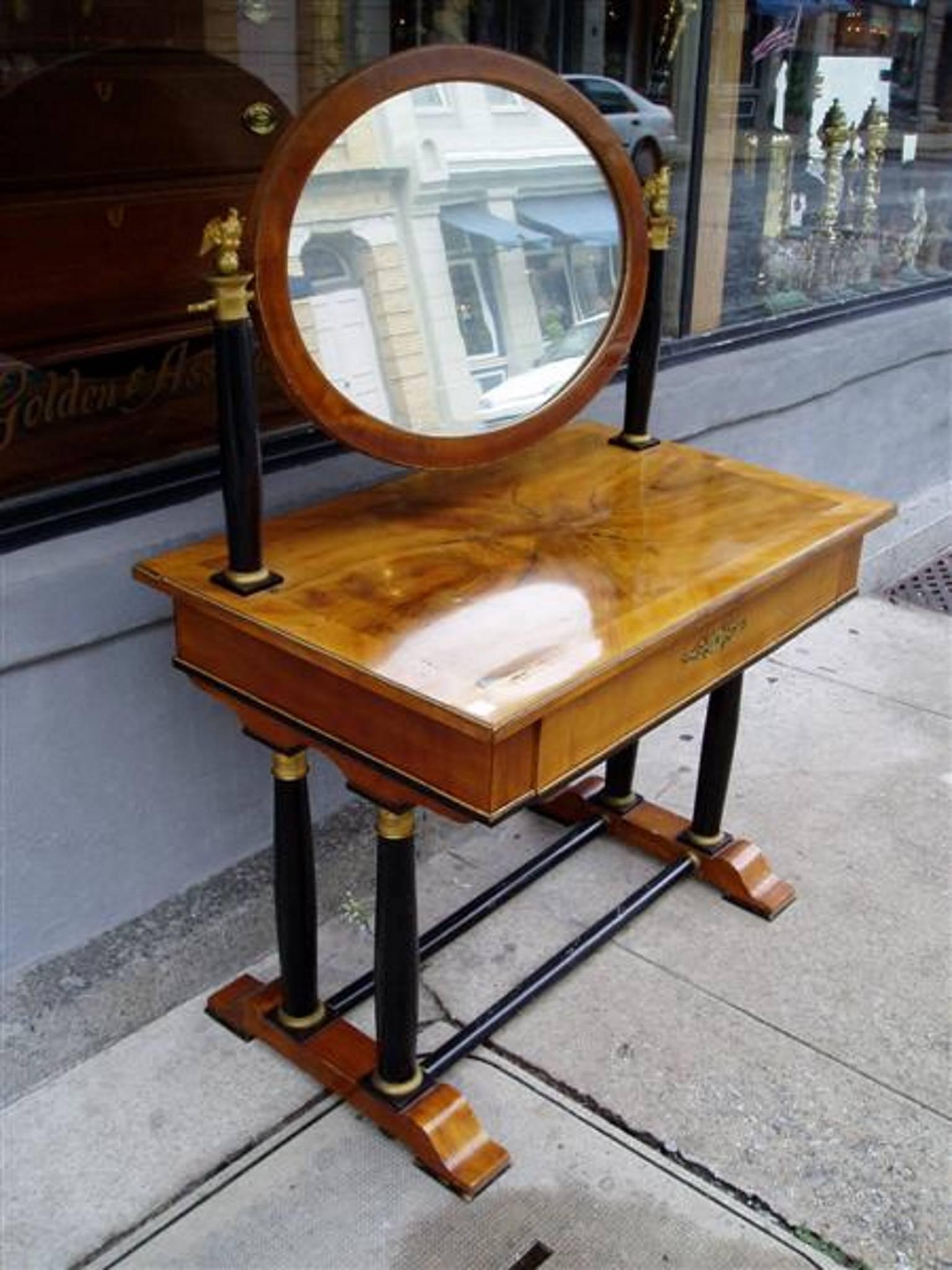 Viennese flame birch veneered dressing table with flanking bronze eagle capitals mounted on ebony columns supporting an adjustable oval veneered framed mirror, centered drawer with beading, ormolu escutcheon and fitted interior, all resting on four